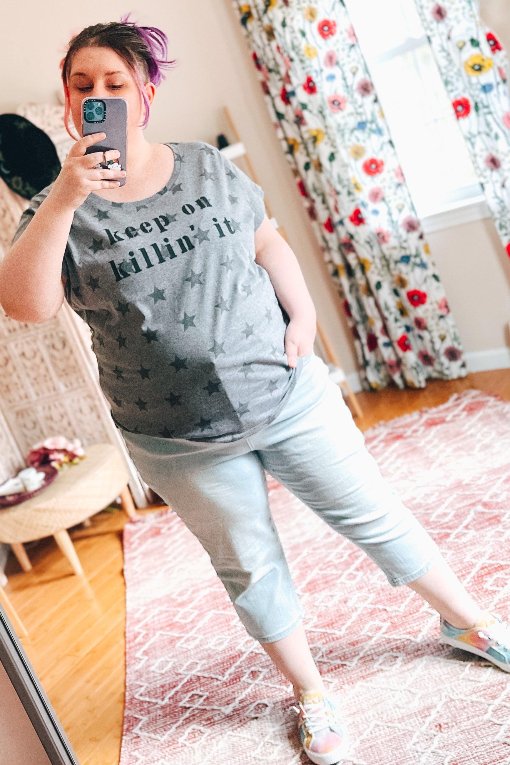 Woman taking mirror selfie wearing grey Keep On Killin’ It Star Tee with star pattern and light-colored capri pants indoors