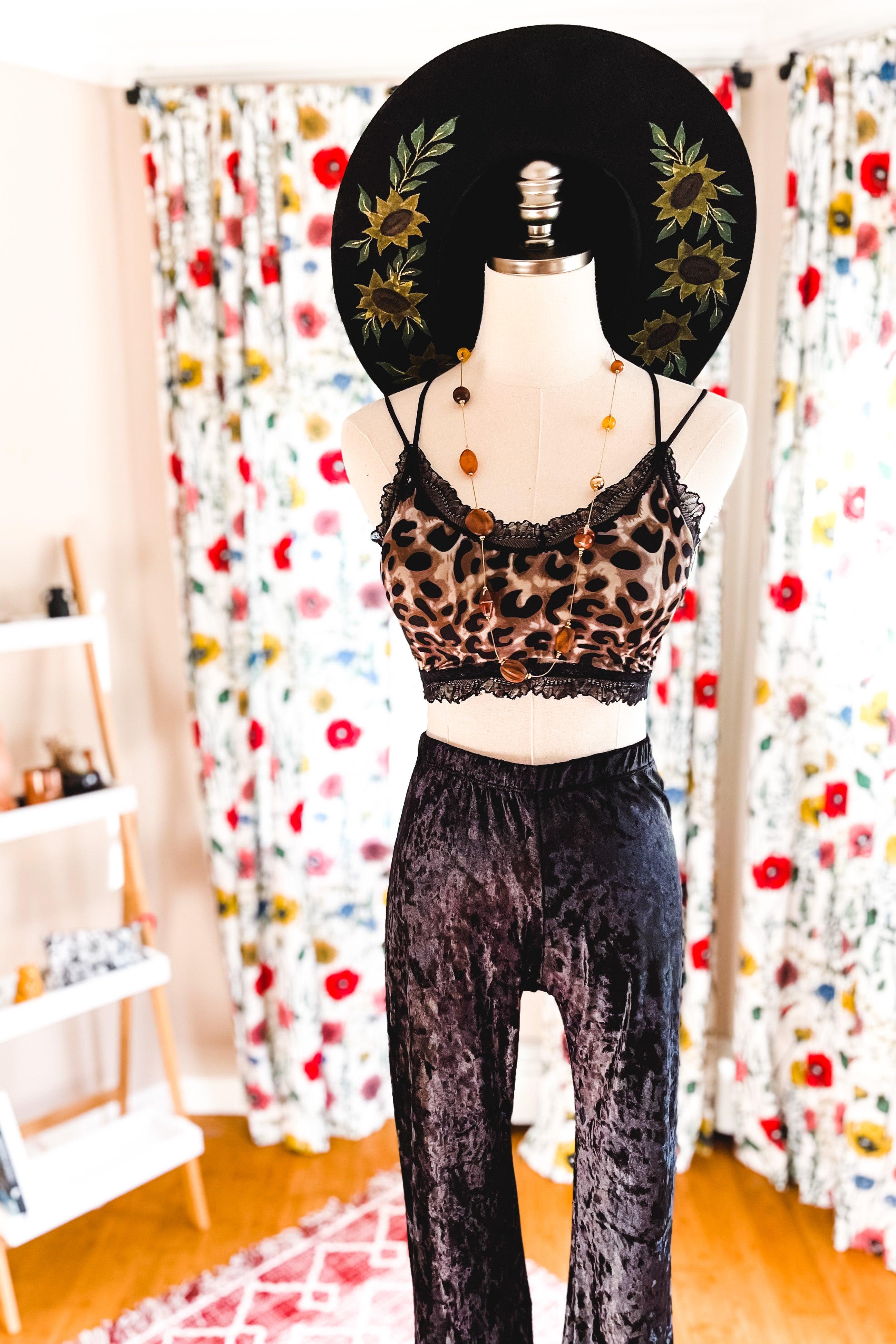 Mannequin wearing brown and black leopard print crop top with black lace trim, black velvet pants, and black floral embroidered hat