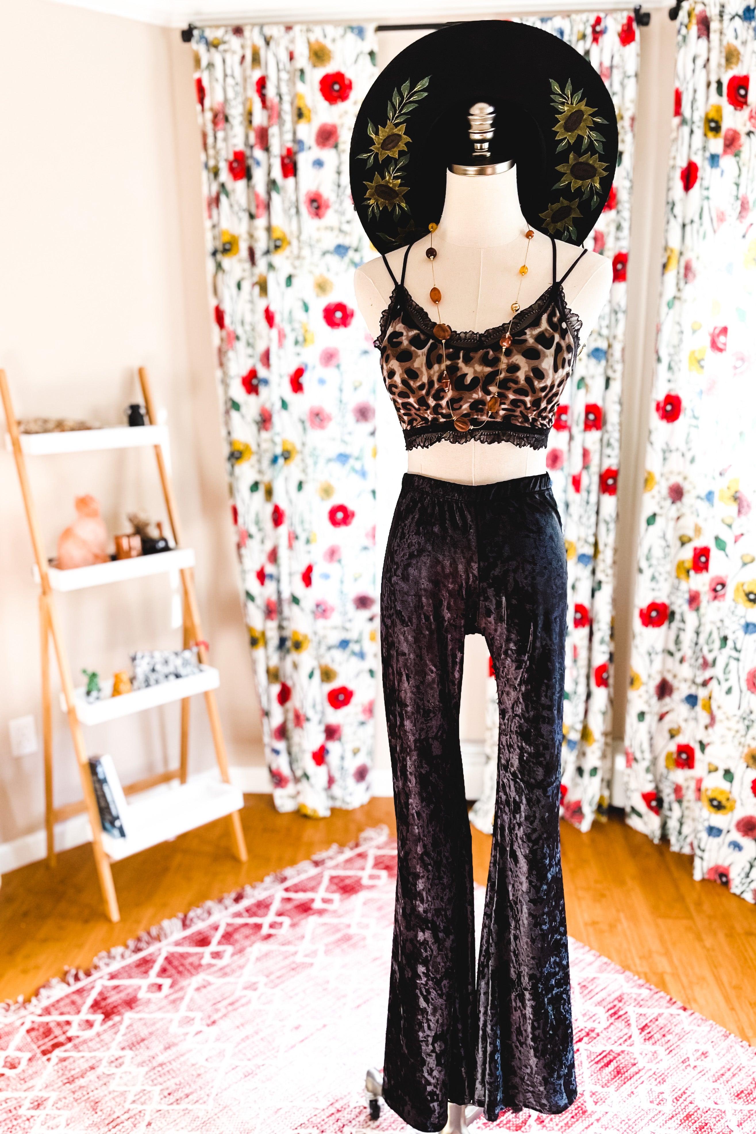 Mannequin dressed in brown and black leopard print crop top with lace trim, black velvet wide-leg pants, and a black hat with floral embroidery