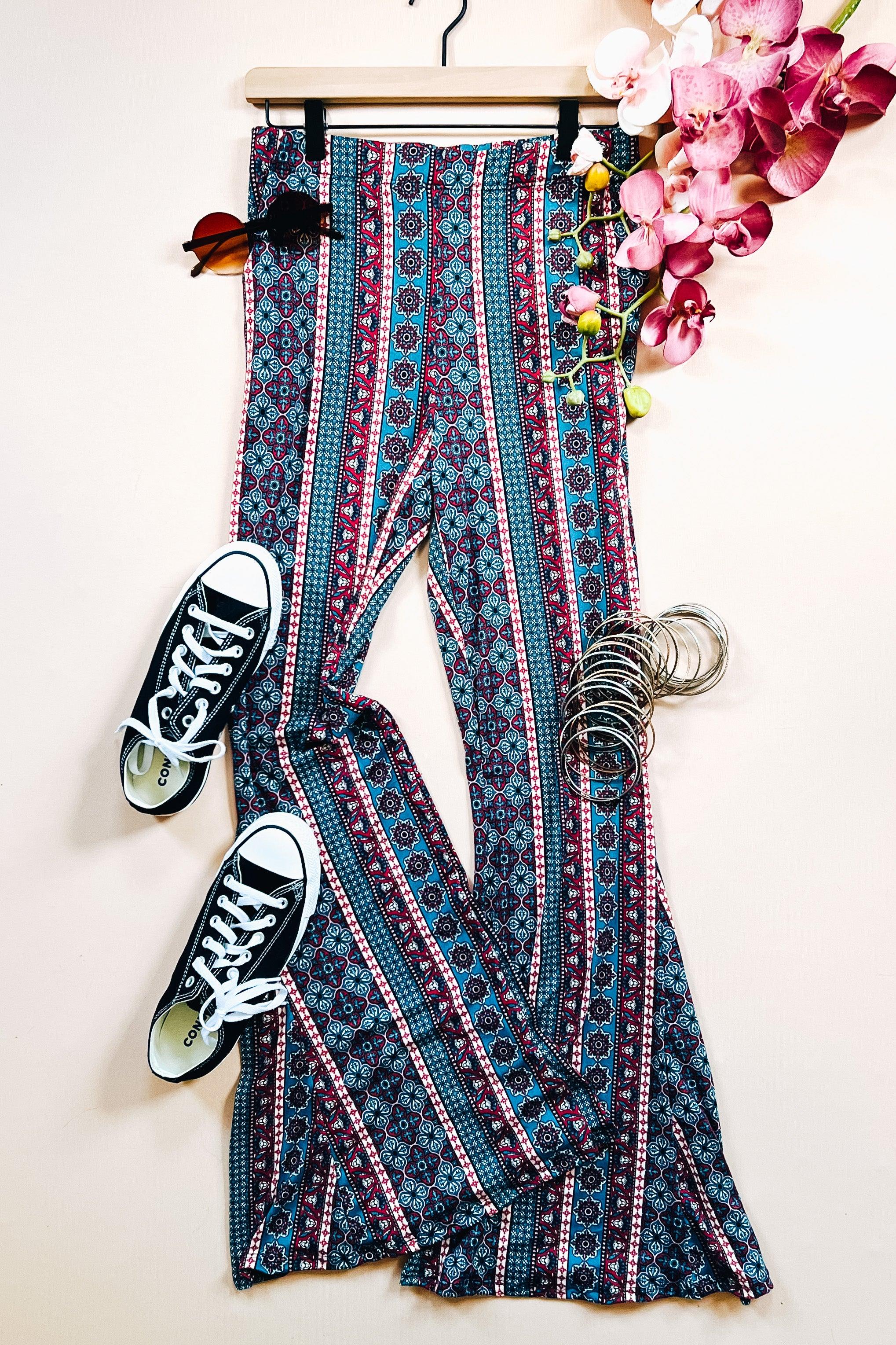 Blue patterned flared pants with vertical stripes styled with black sneakers and silver bangles on a light background