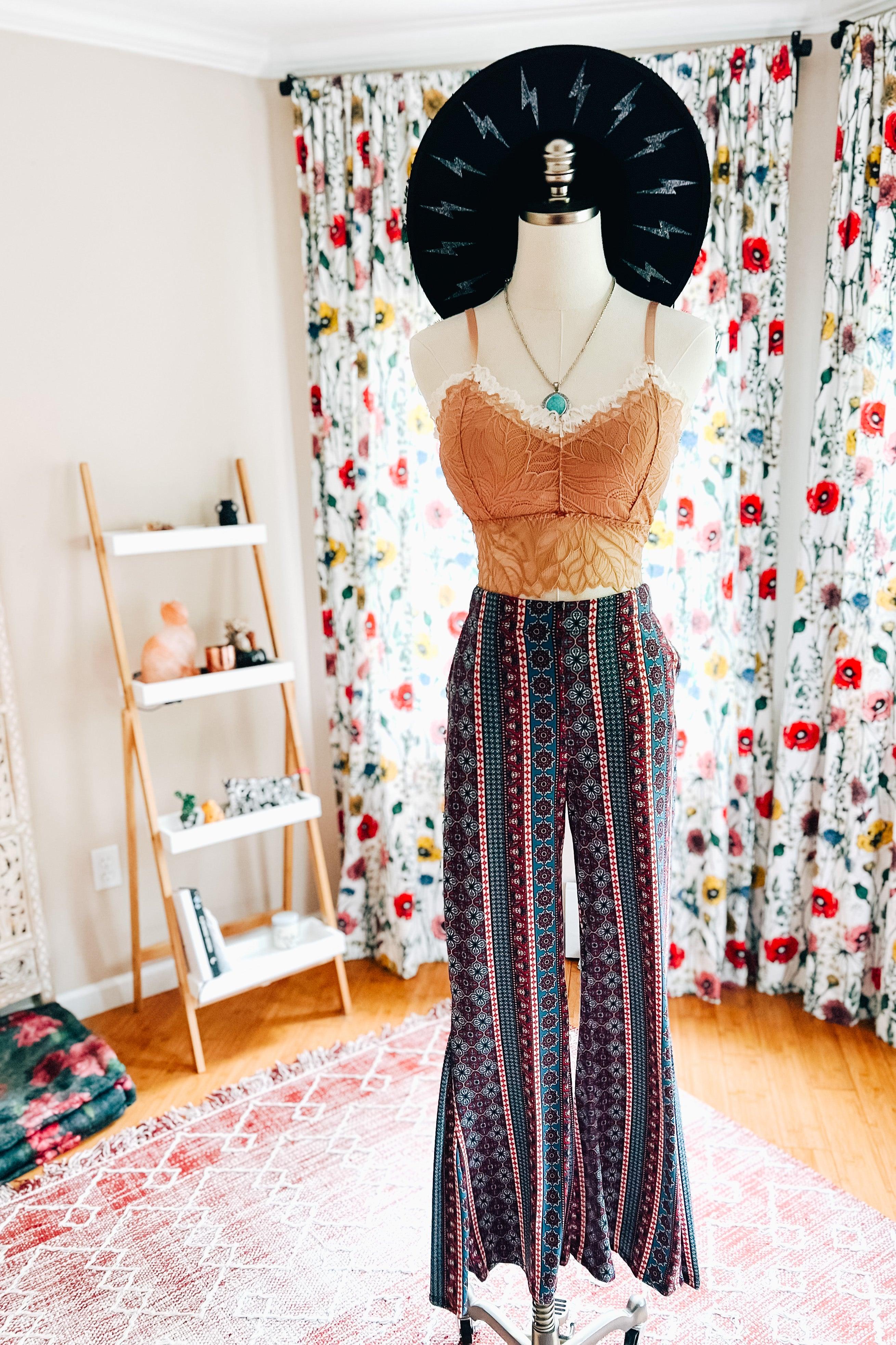 Mannequin dressed in patterned wide-leg pants with vertical stripes and a lace-trimmed rust-colored crop top and black hat