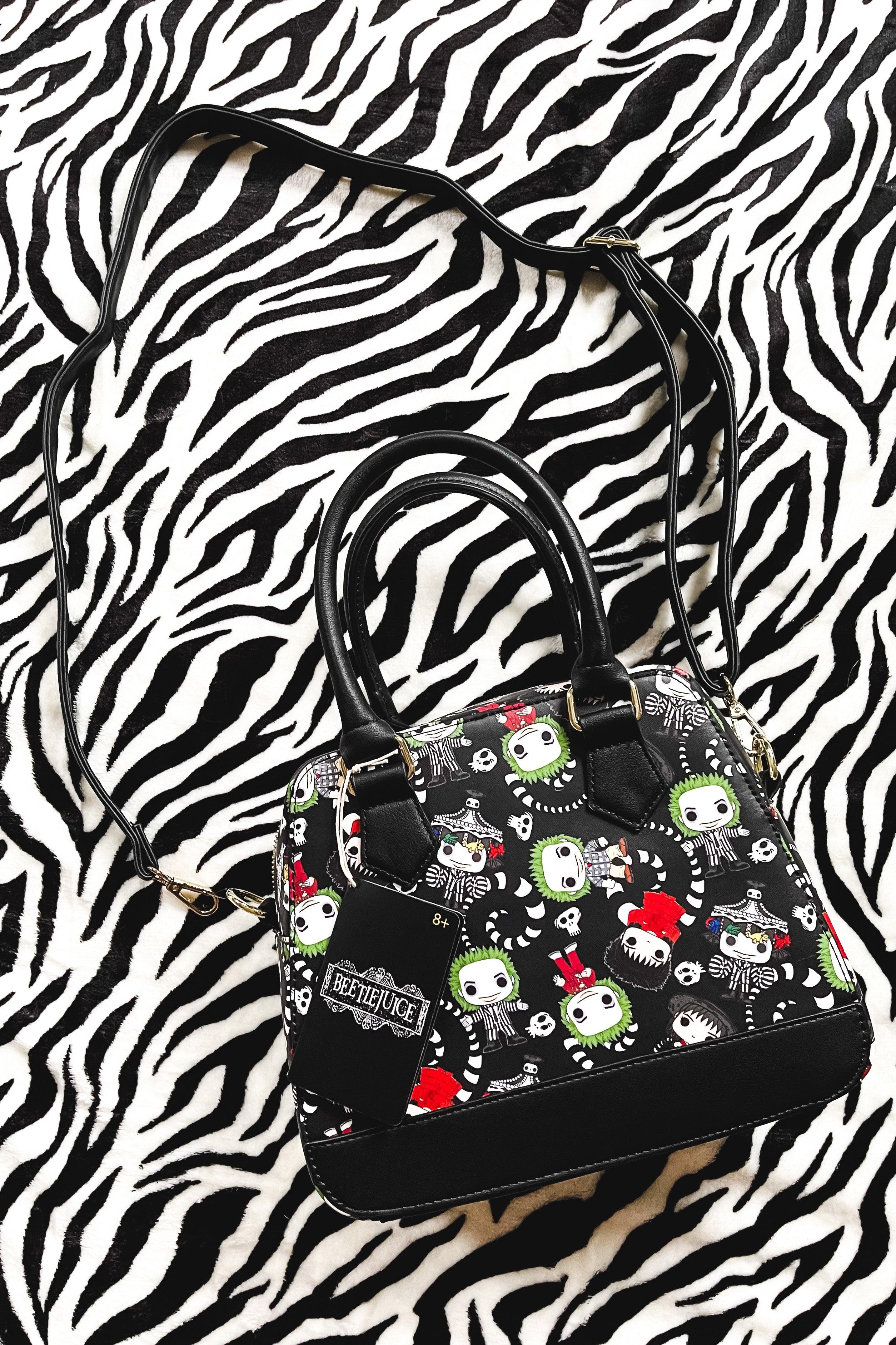 Black loungefly handbag with colorful beetlejuice faces and skeletons on black background with black handles and trim