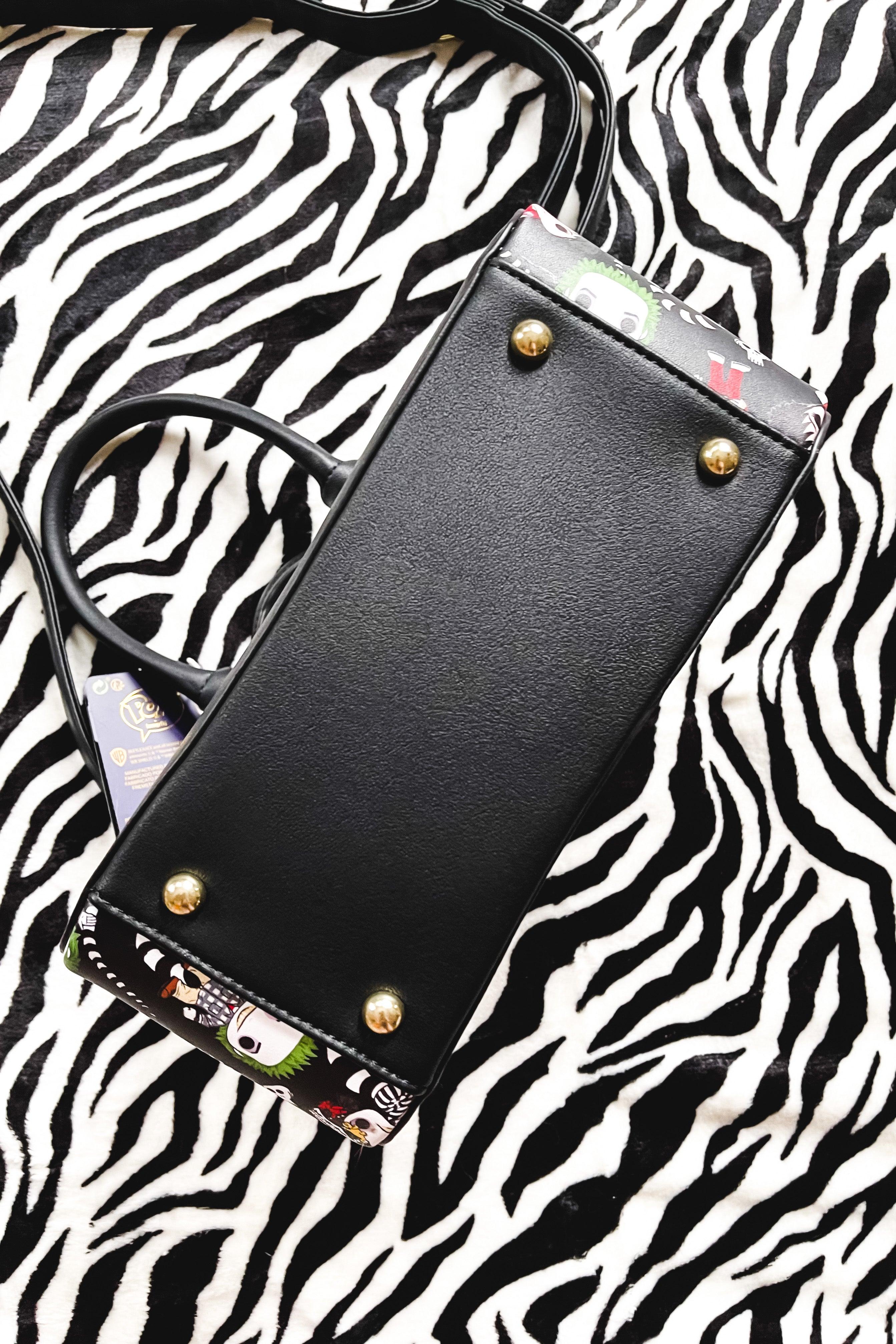 Black loungefly handbag bottom with gold feet and partial colorful character design on a zebra print fabric background