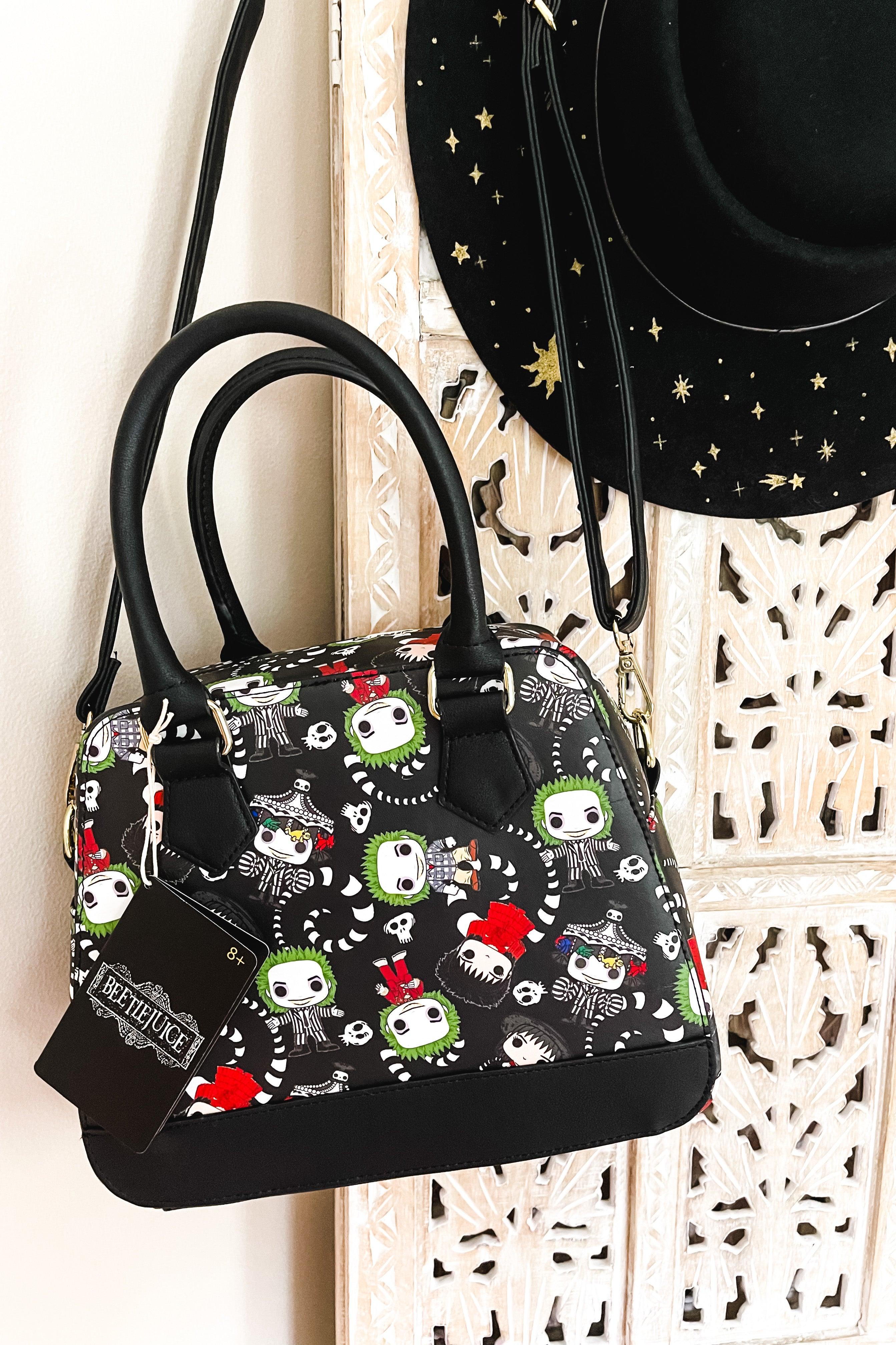 Black loungefly handbag featuring colorful Beetlejuice cartoon characters with skull accents and black handles hanging against carved wood panel background