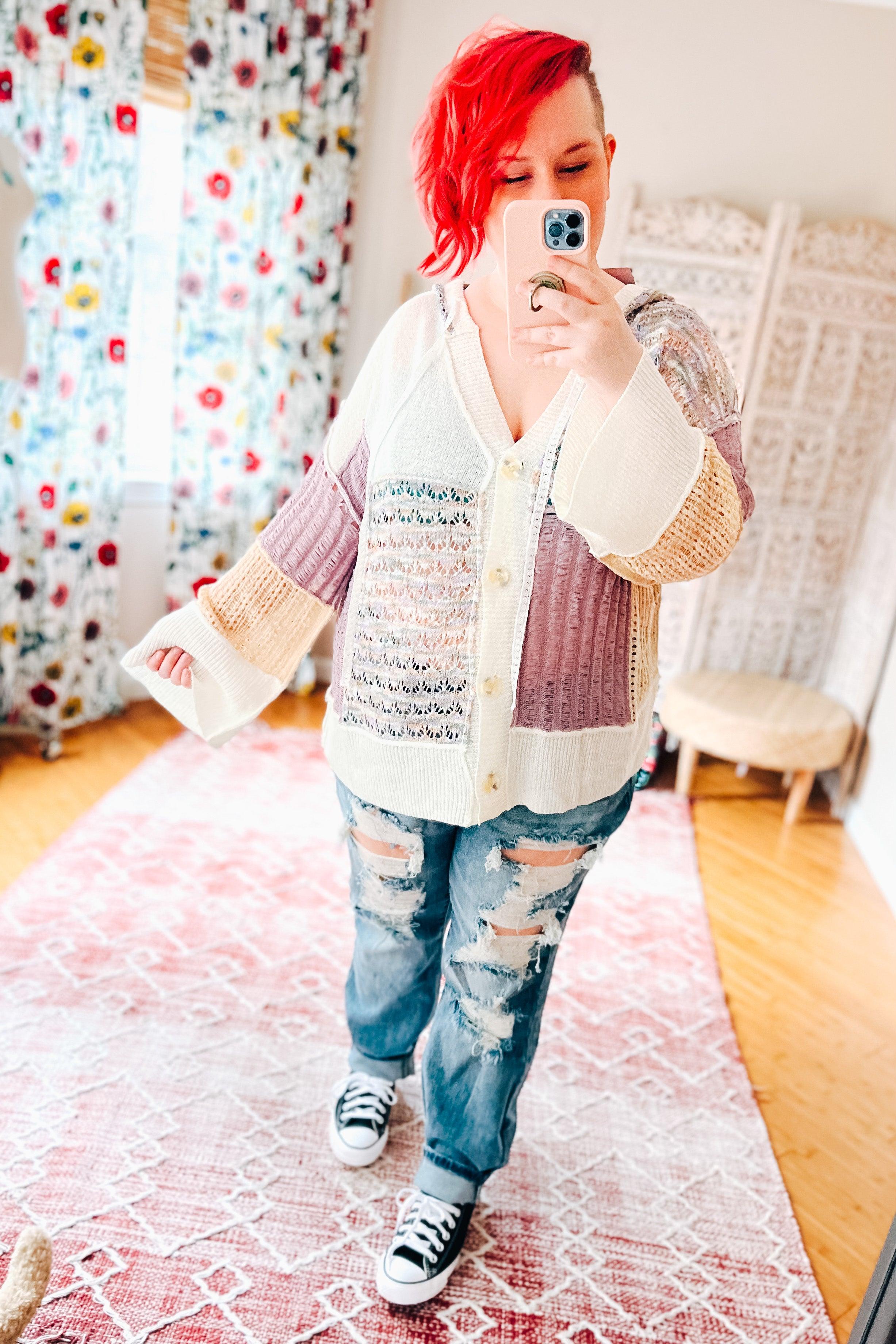 Casual patchwork knit cardigan with lavender, cream, and beige panels worn with distressed jeans and sneakers indoors