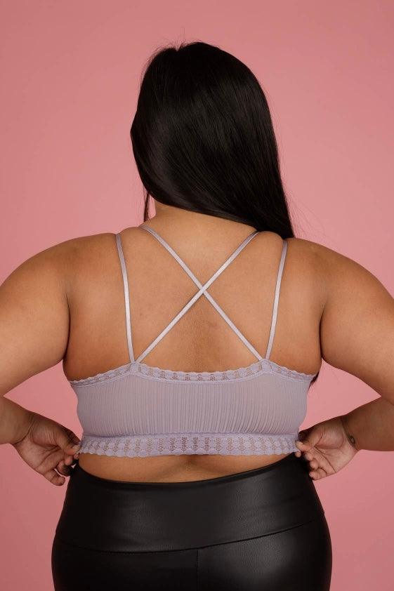 Back view of a lilac ribbed lace bralette with crisscross thin straps worn by a woman against a pink backdrop