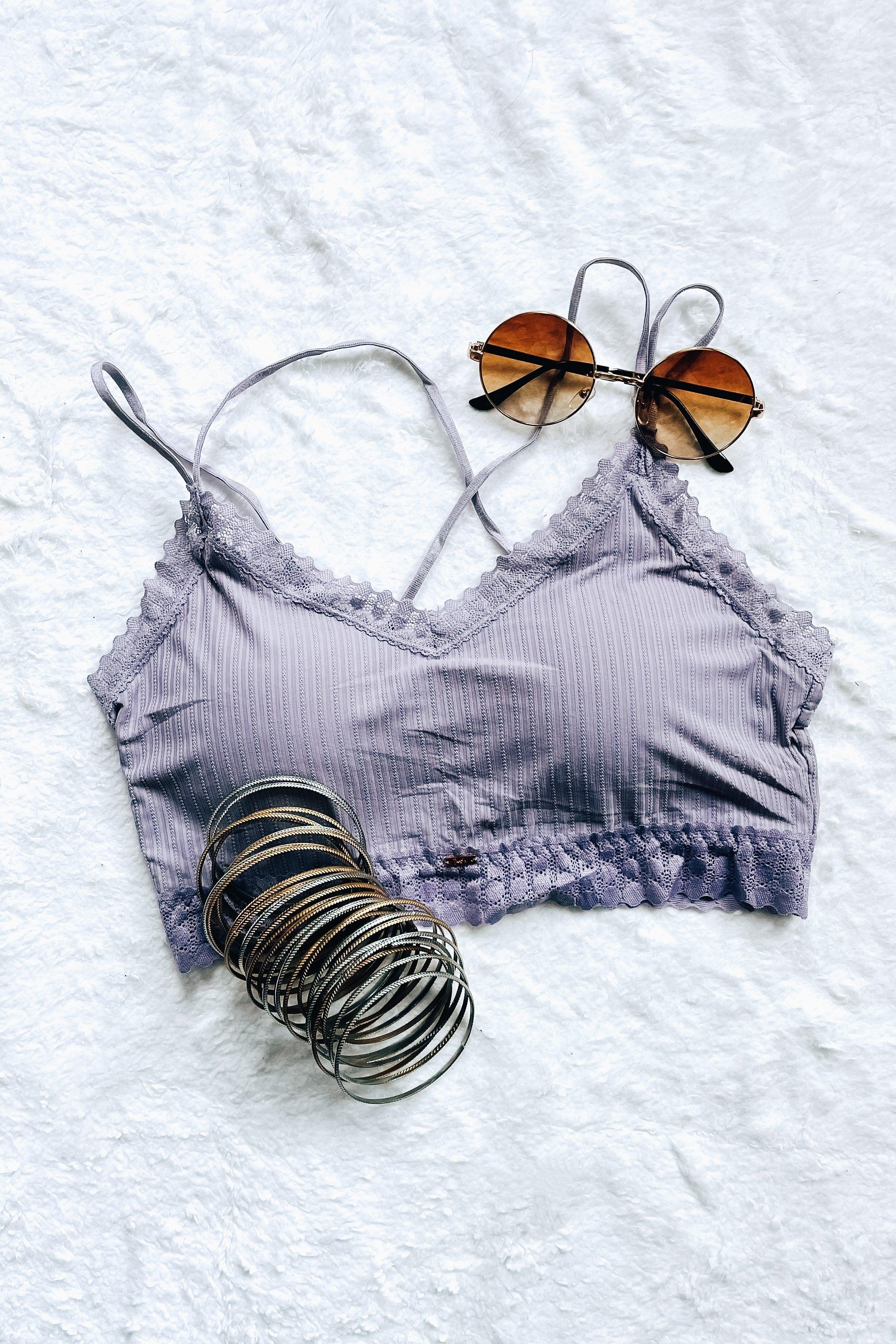 Lilac lace bralette with ribbed fabric and scalloped trim styled with round sunglasses and silver bangles on white surface