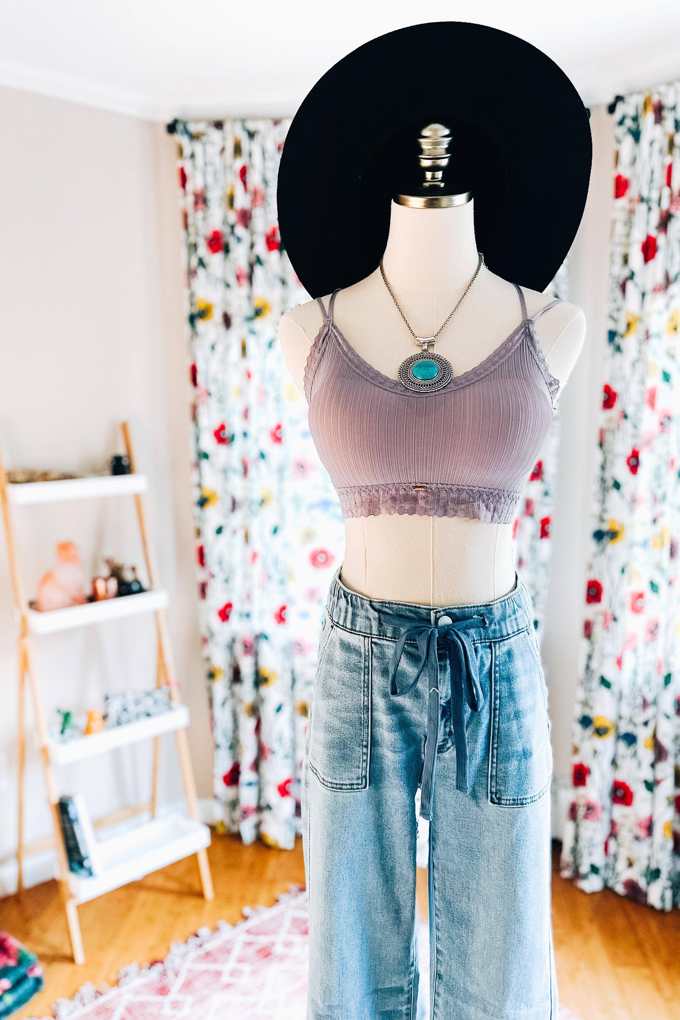 Lilac ribbed bralette with lace trim styled on mannequin with high-waisted denim pants, pendant necklace, and black wide hat