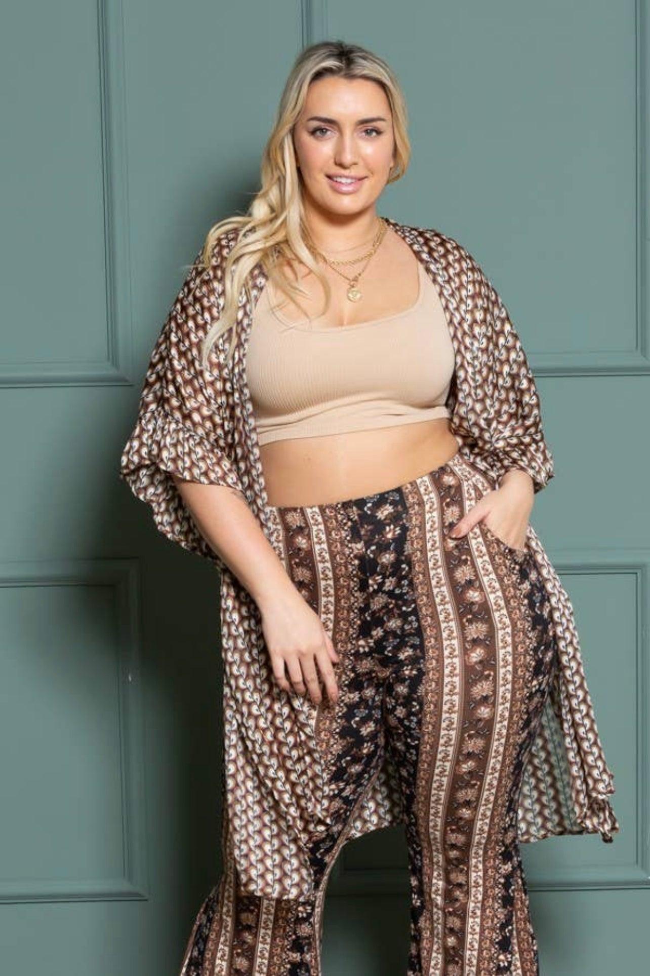 Curvy woman wearing brown patterned cozy kimono over paisley print bell bottoms and a beige crop top