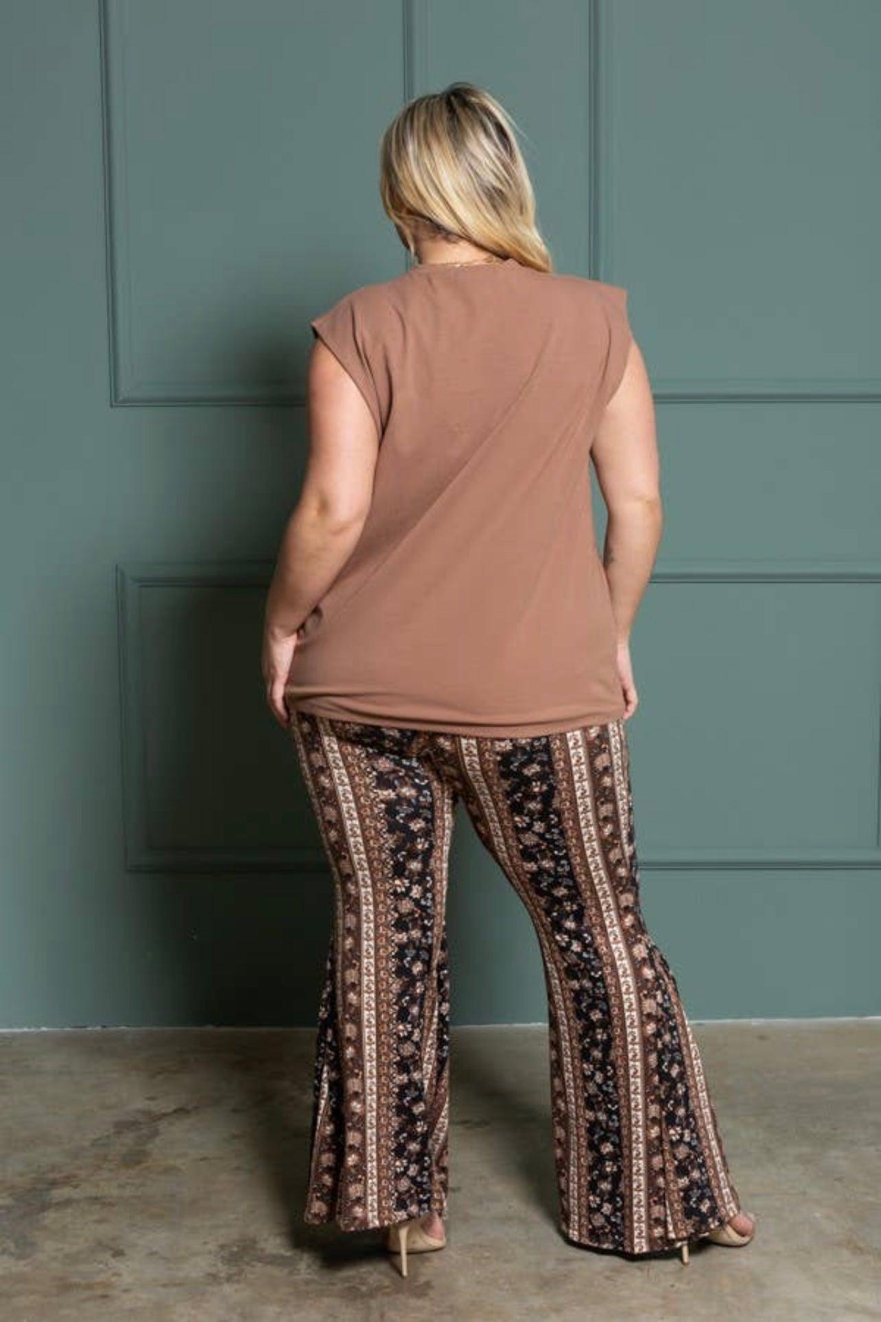 Curvy woman wearing brown patterned bell bottoms with vertical stripes and a relaxed brown sleeveless top standing indoors