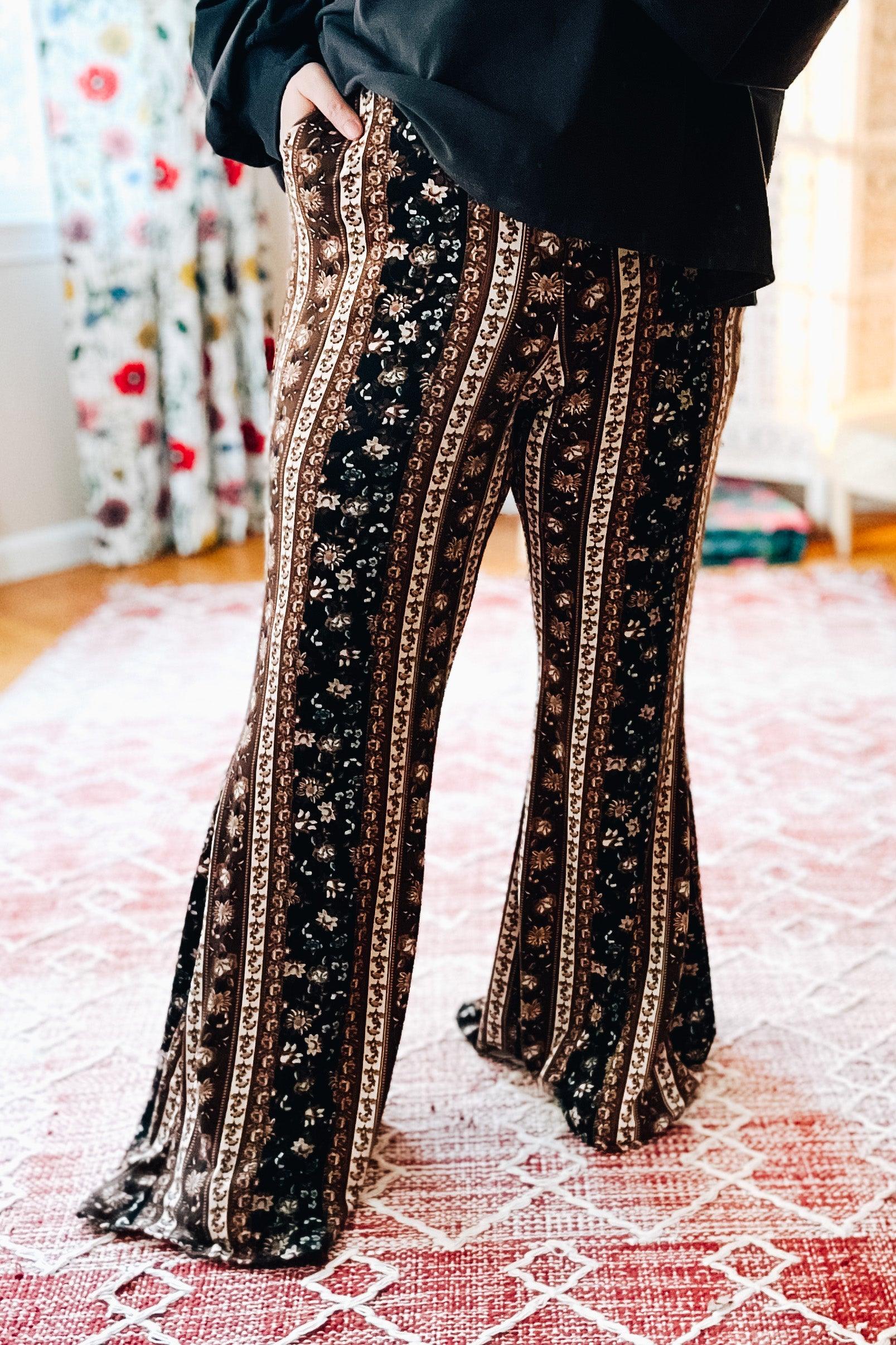 Woman wearing brown and navy paisley printed bell bottoms with hands in pockets standing indoors on patterned rug