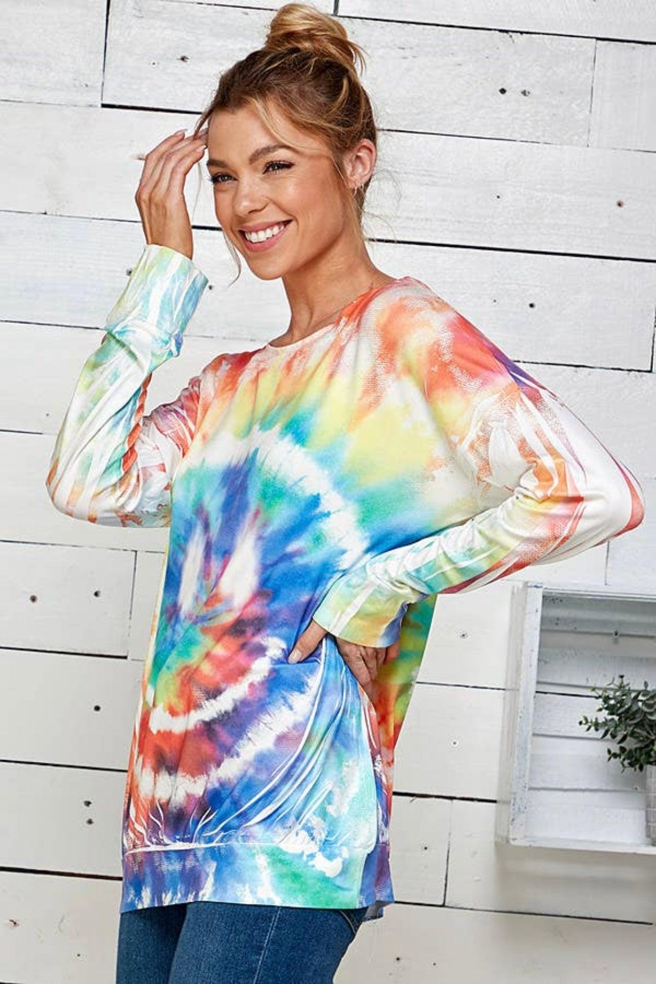 Smiling woman wearing a colorful tie dye rainbow pullover with relaxed fit and pockets in a bright indoor setting