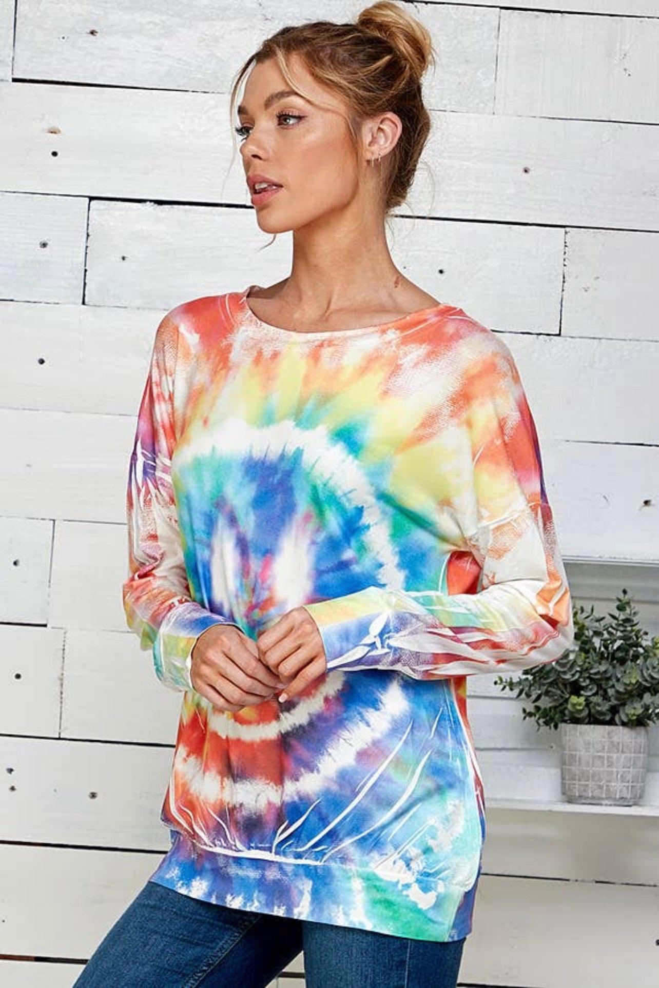 Woman wearing a tie dye rainbow pullover with relaxed fit and long sleeves in a bright casual setting