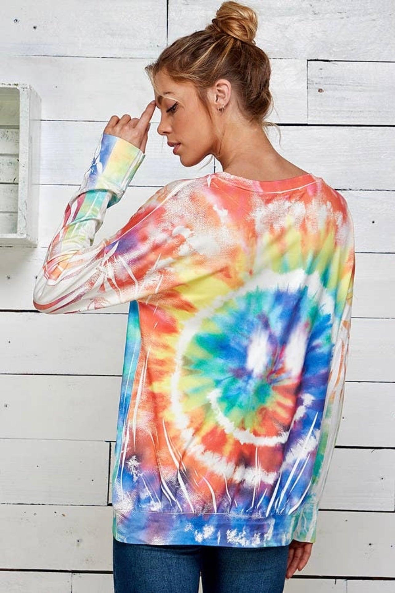 Woman wearing a vibrant tie dye pullover with swirl pattern and long sleeves in a relaxed, free spirited style