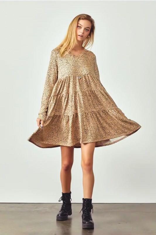 Woman wearing taupe animal print V neck dress with flowing tiered skirt and black combat boots standing against plain background