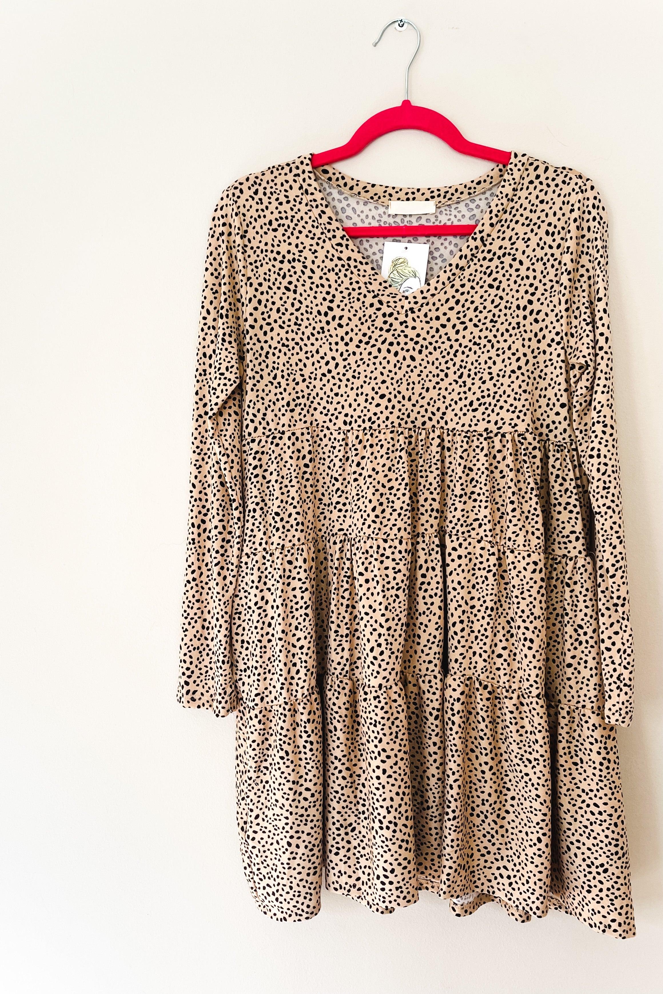 Taupe animal print dress with V neckline and long sleeves, hanging on a pink hanger against a white background