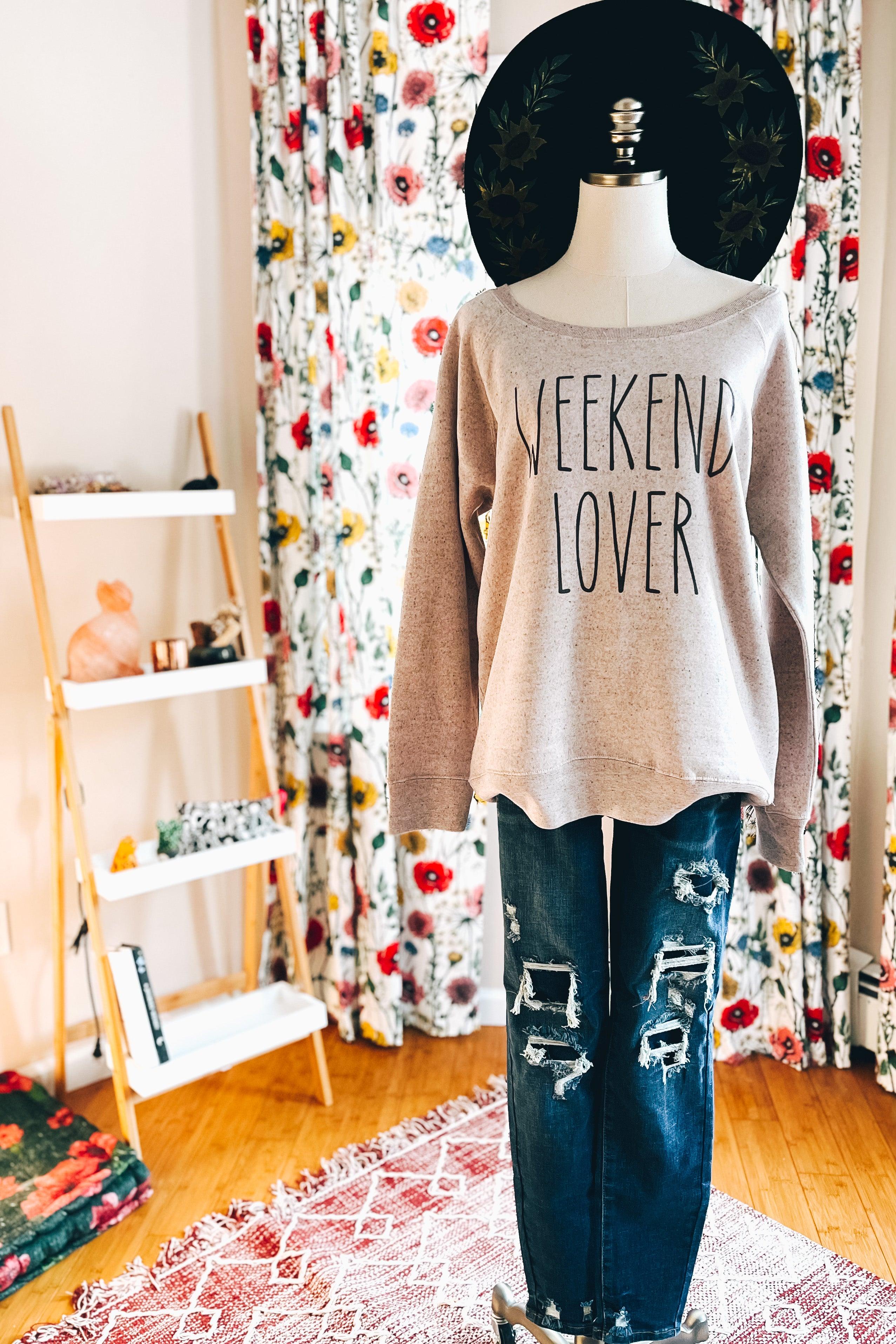 Mannequin dressed in blush scoop neck pullover with weekend lover text and distressed blue jeans indoors with floral curtains