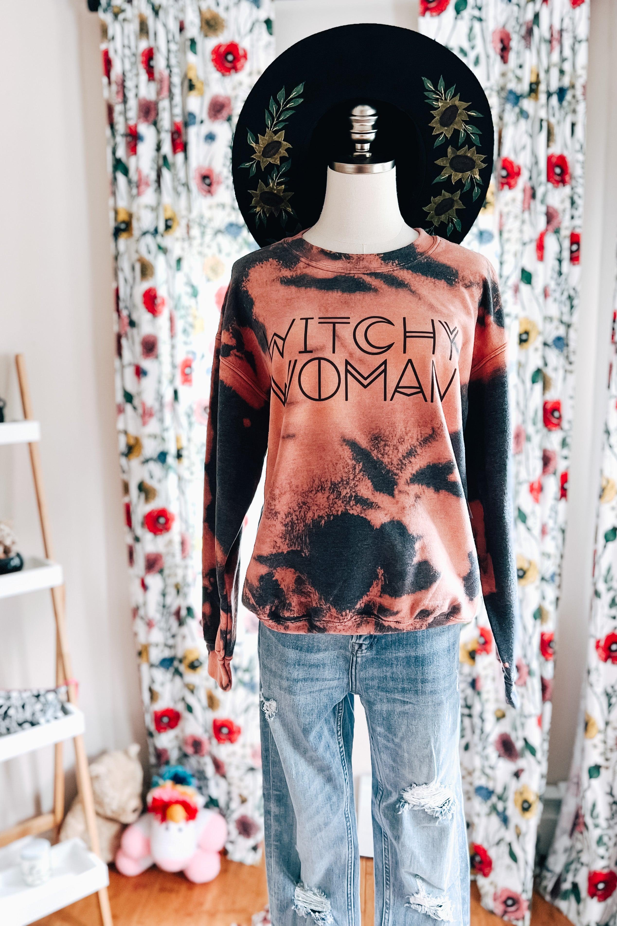 Mannequin wearing bleach-dyed sweatshirt with "Witchy Woman" text and ripped light blue jeans indoors with floral curtains