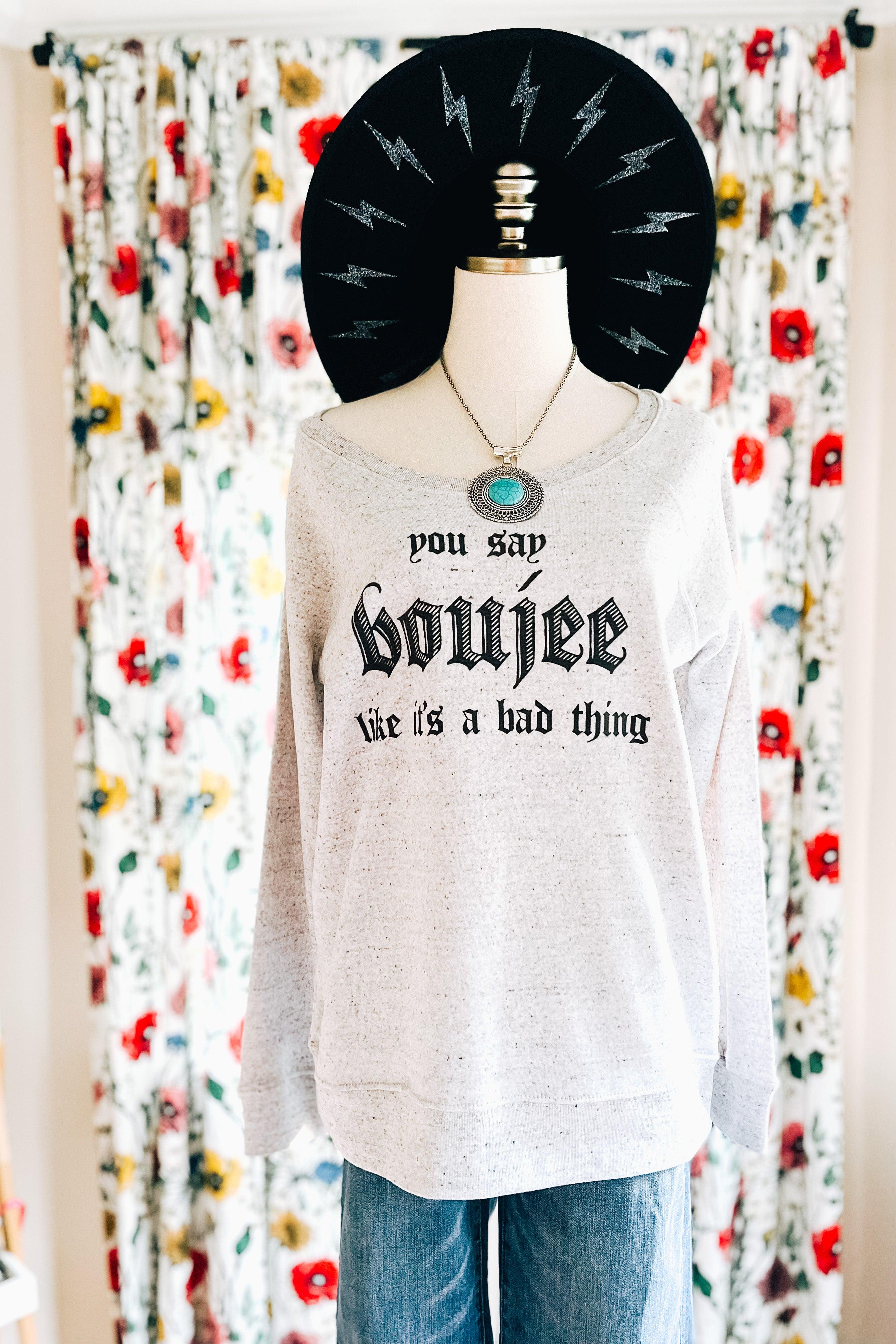 Grey speckled pullover with bold gothic text paired with turquoise necklace and black lightning bolt hat on mannequin