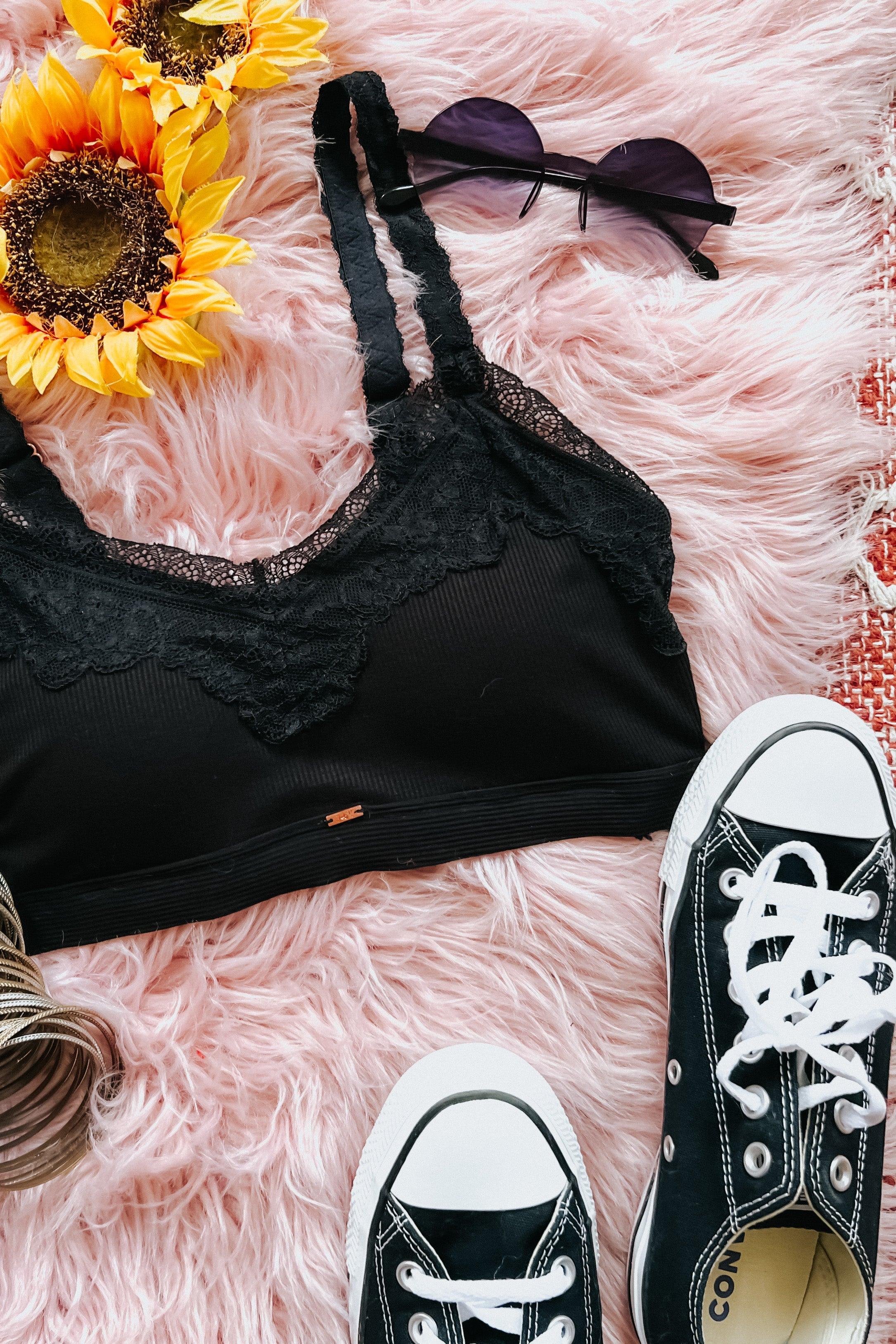 Black lace-trim bralette styled with retro sunglasses, black canvas sneakers, and vibrant sunflowers on soft pink fur