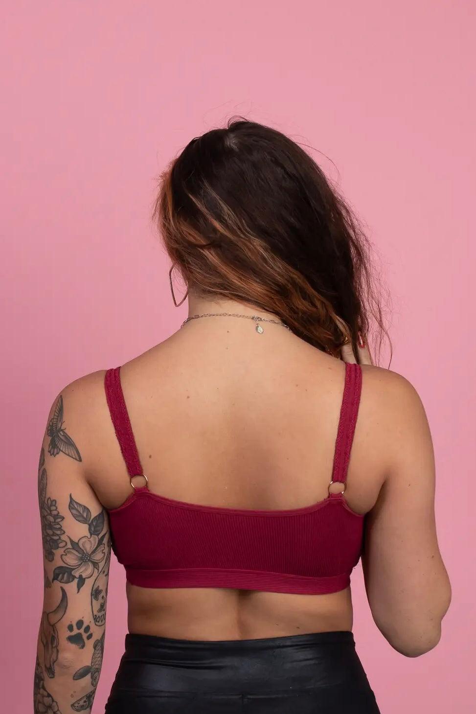 Back view of woman with floral and paw print tattoos wearing wine-colored lace trim bralette with adjustable straps