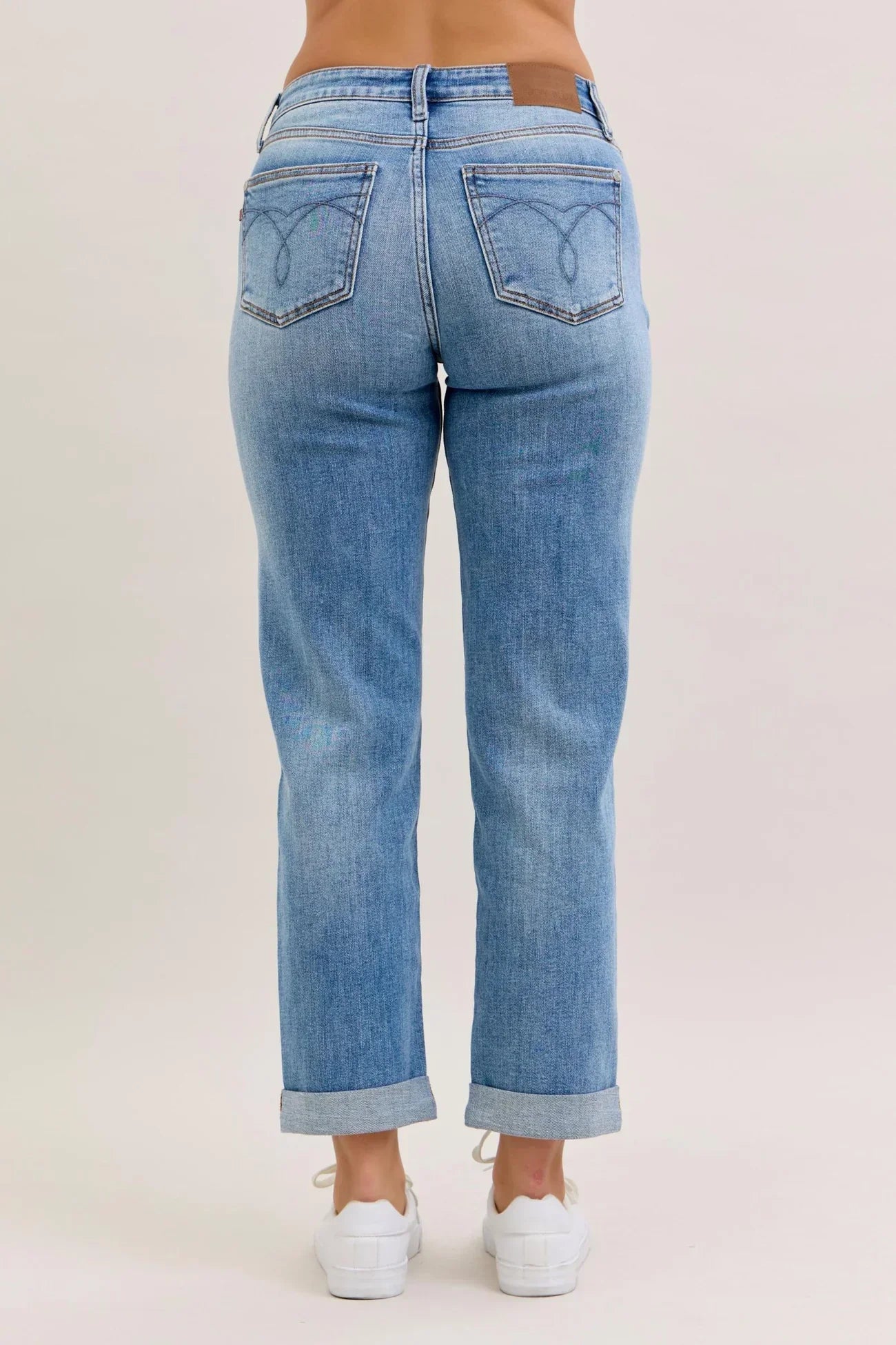 Back of light blue jeans worn by a person on a plain background