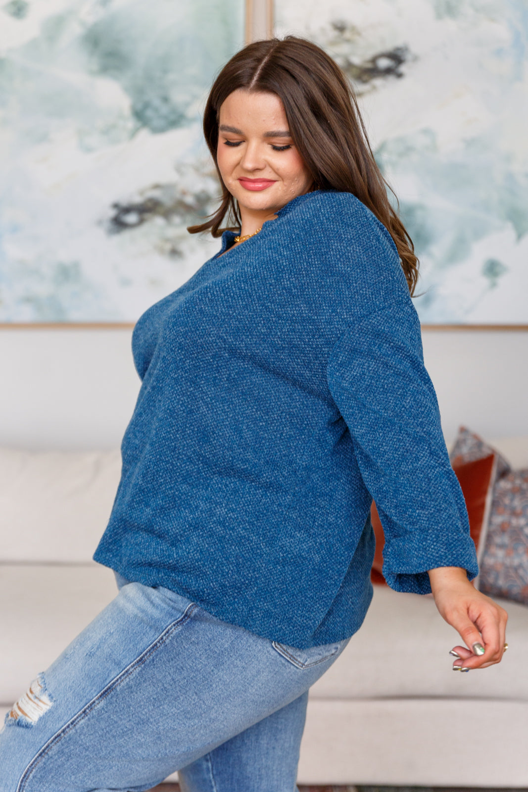 Woman wearing a blue sweater and blue jeans in a living room setting