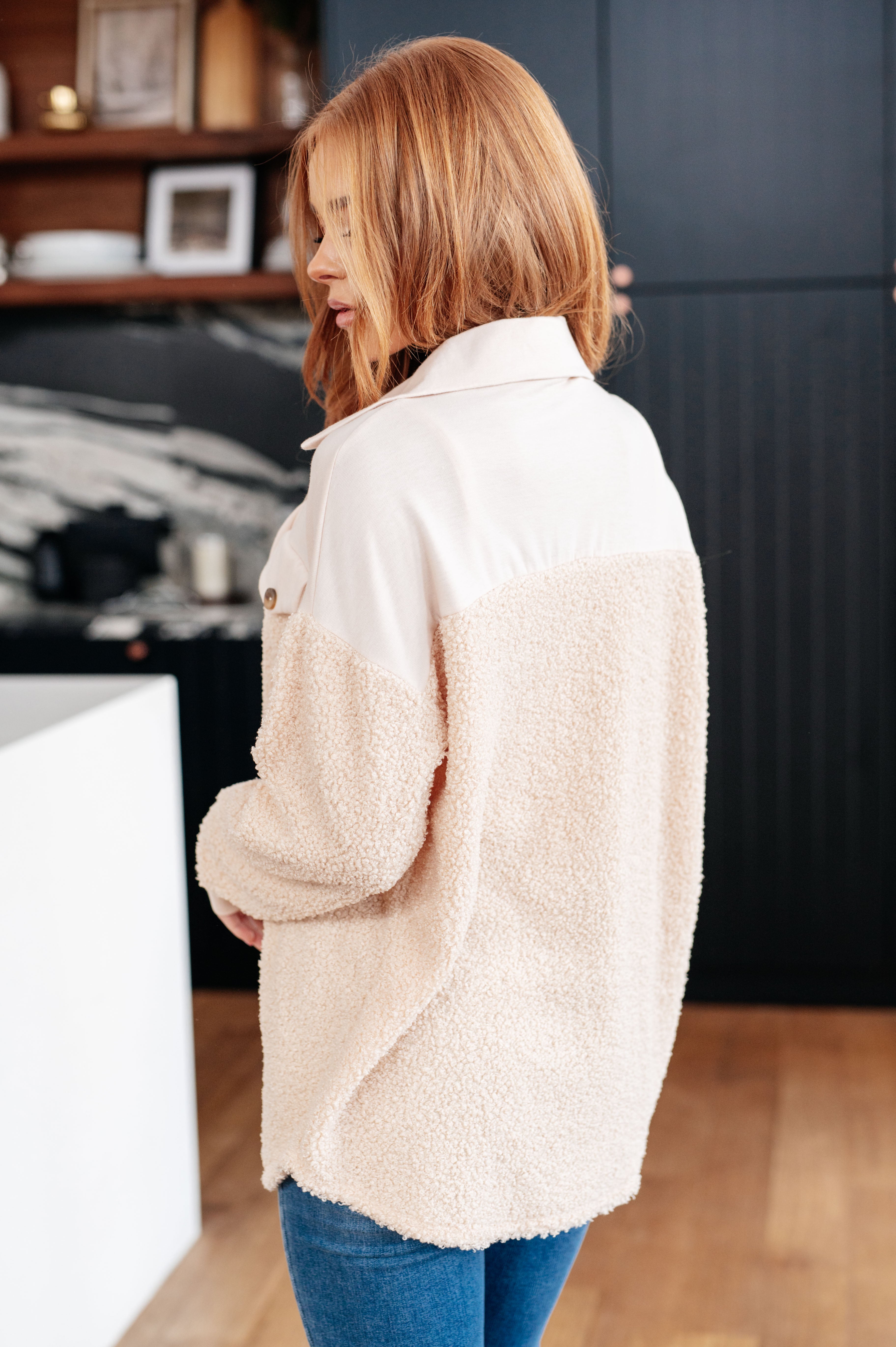 Woman wearing a beige fleece shacket in a kitchen setting