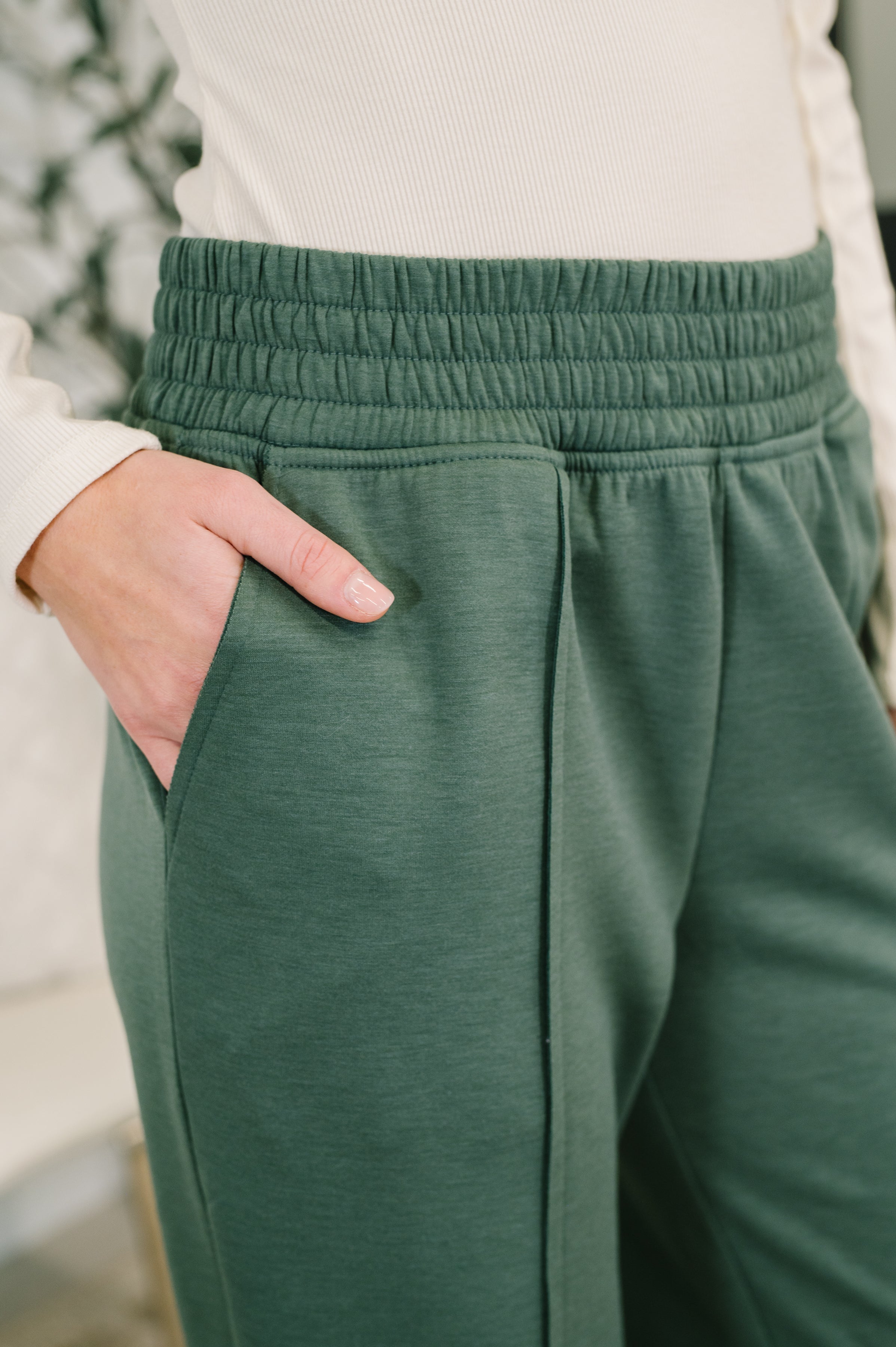 Green jogger pants worn by a woman with a blurred background