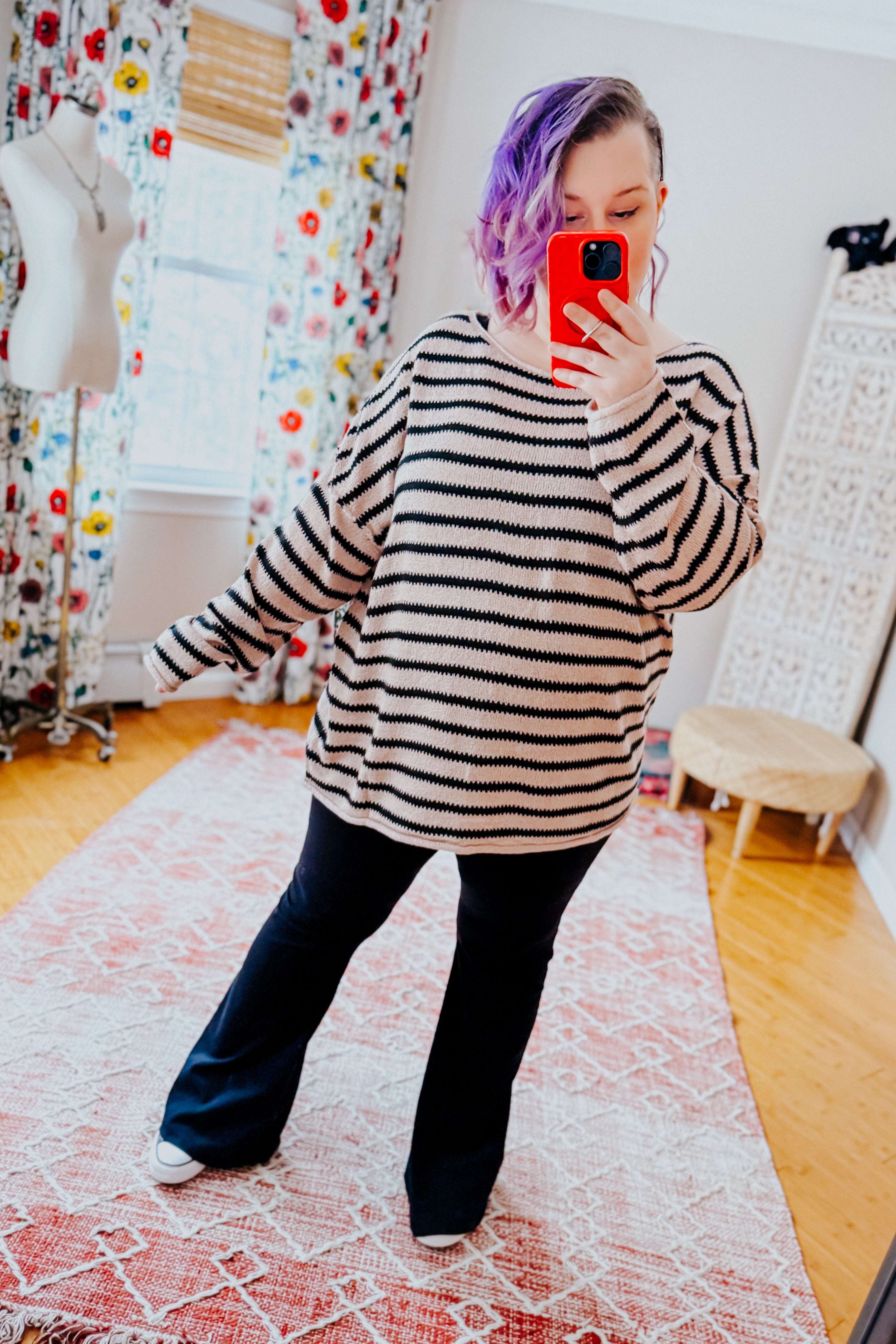 Woman wearing a taupe long sleeve sweater with black stripes and yoga pants in an indoor setting.
