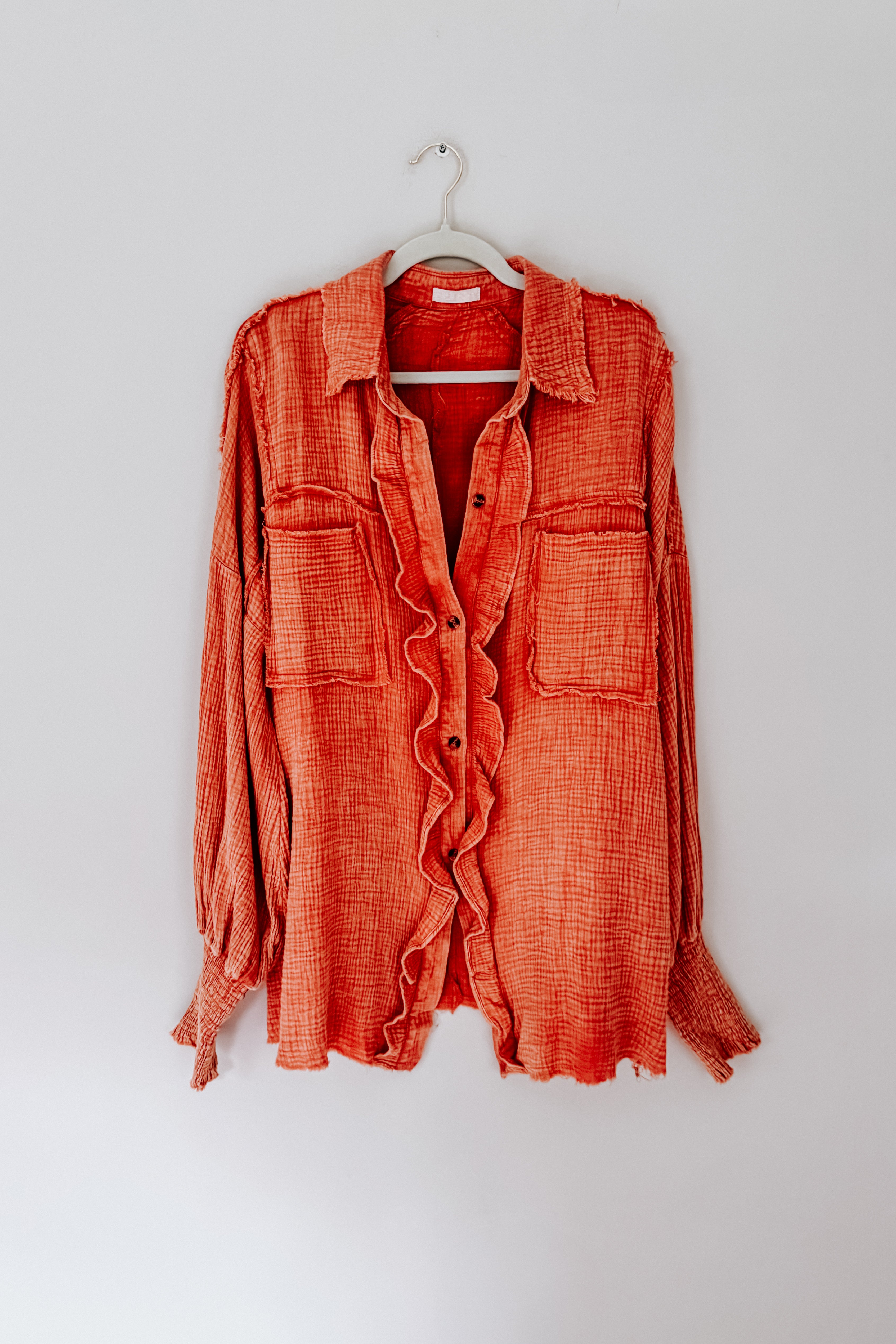 Orange All Pan Out Ruffled Button Up Shirt with textured fabric and two chest pockets hanging against white background