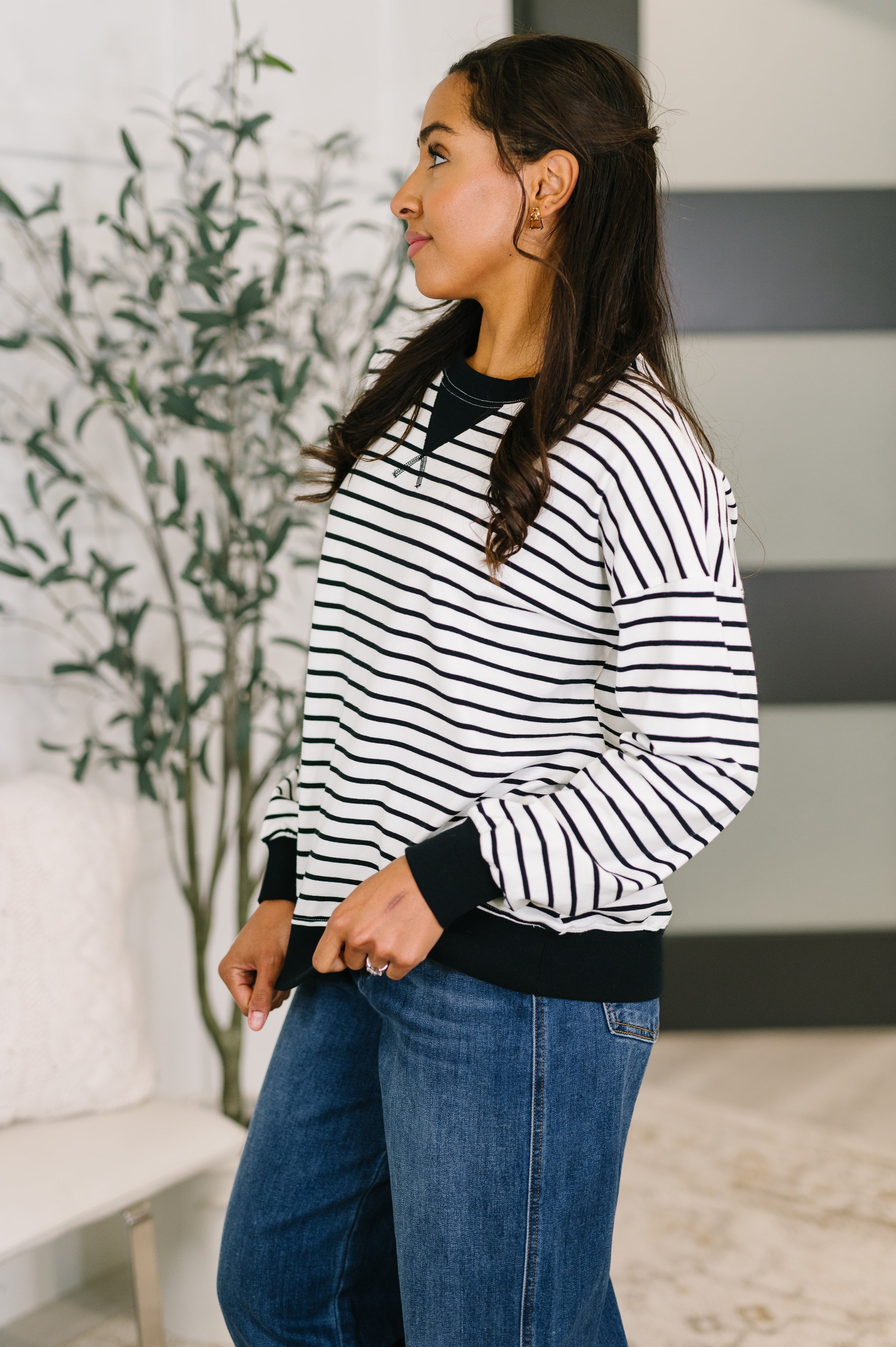 Profile view of woman wearing black and white striped Almost Therapeutic Drop Shoulder Pullover with black cuffs and hem indoors