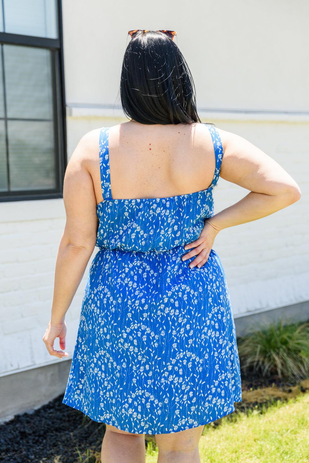 Woman wearing a blue floral dress standing outdoors.