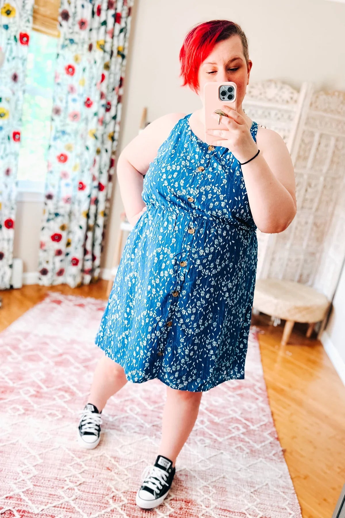 Woman wearing a blue floral dress standing indoors.