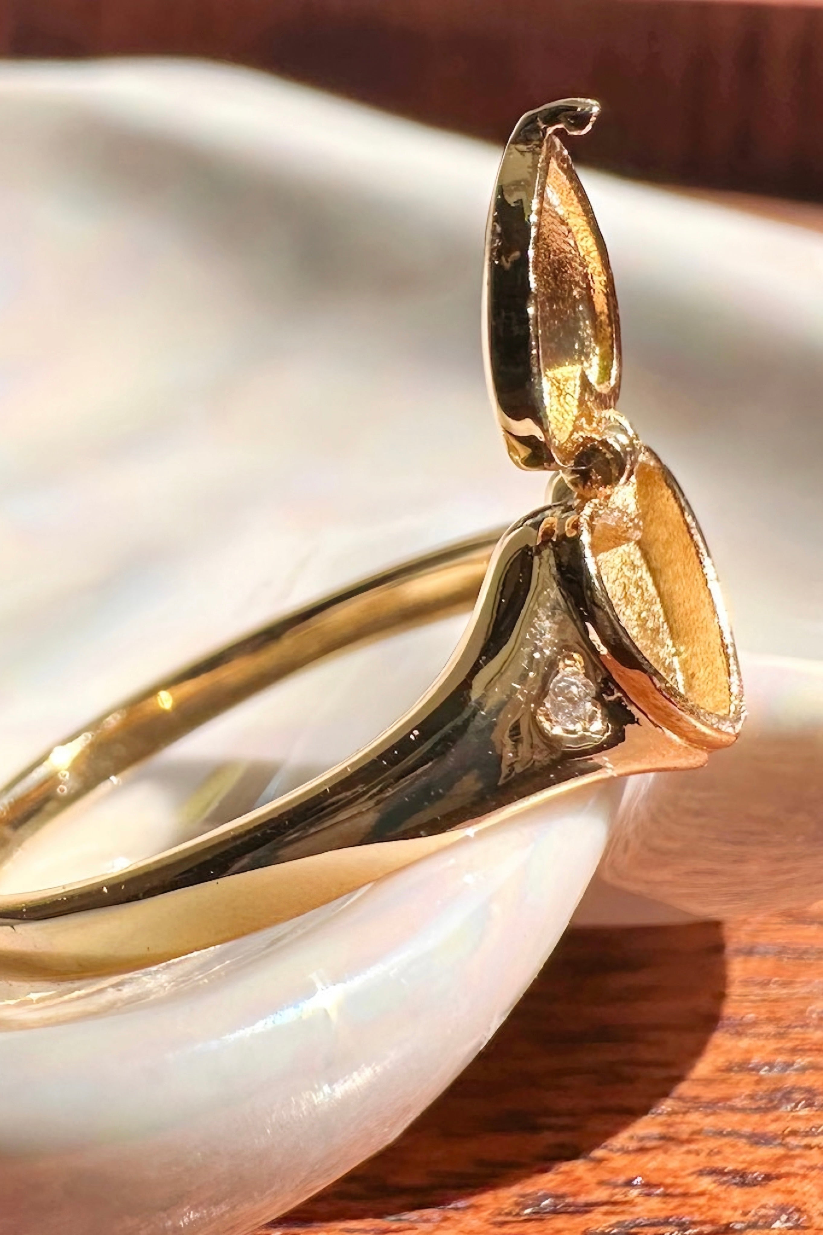 Close-up of open gold heart locket ring revealing inner compartment with small diamond detail on smooth band