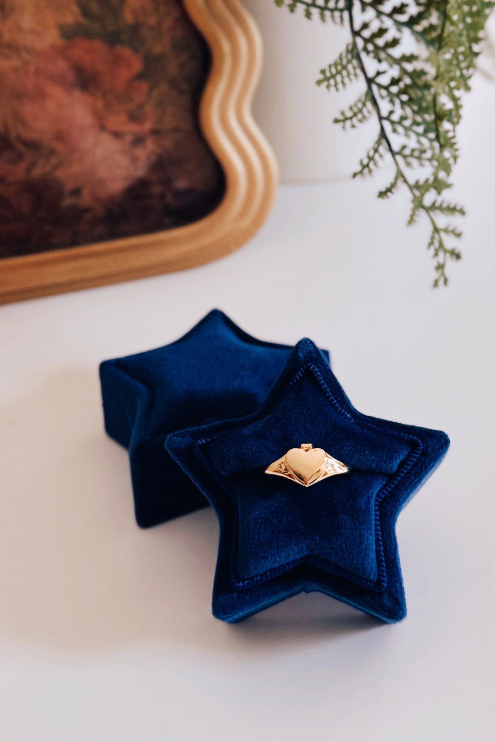 Aurelia Heart Locket Ring resting inside a blue star-shaped velvet ring box on white surface with blurred background