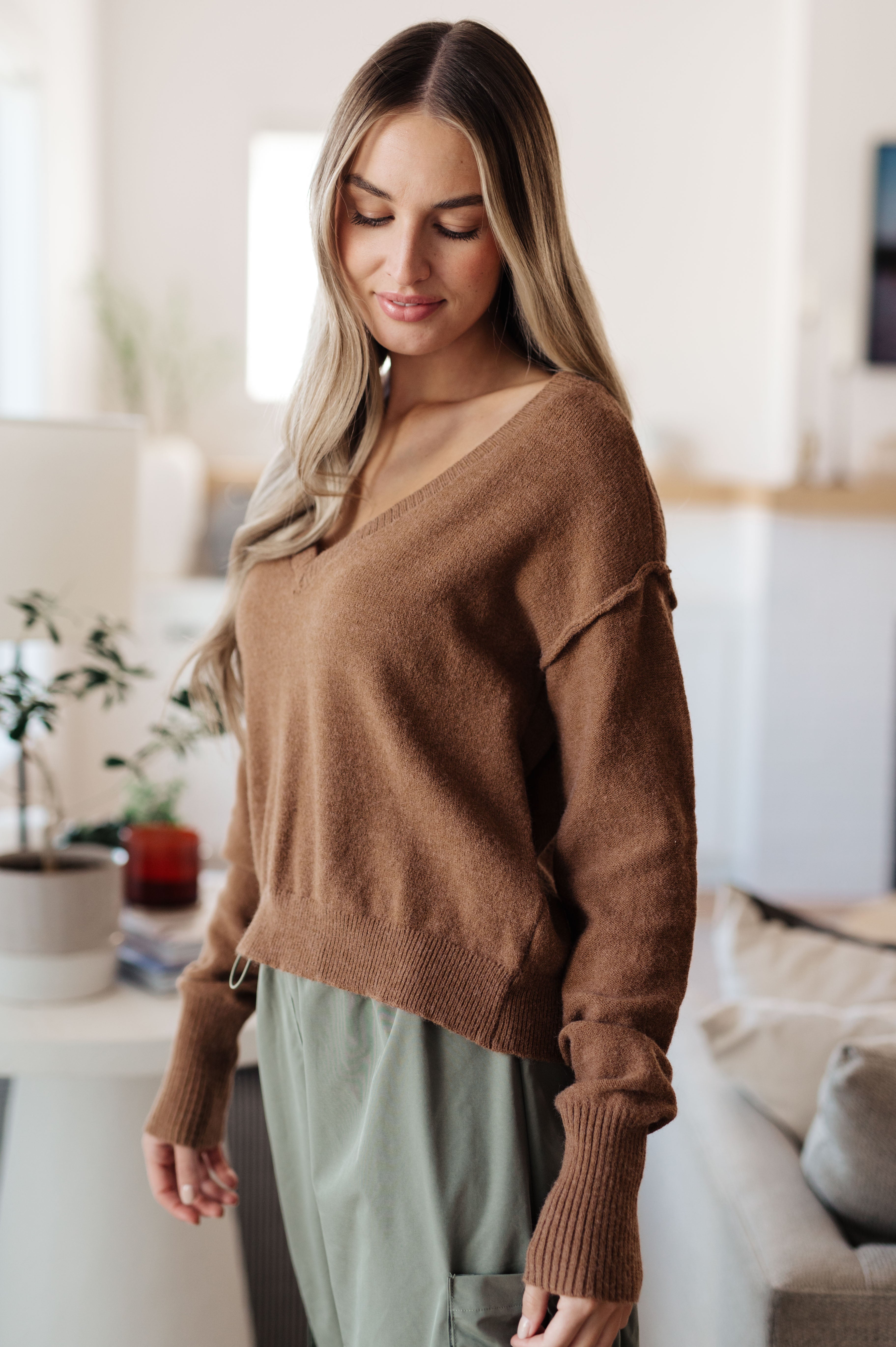 Woman wearing mocha Back to Life V-Neck Sweater with dropped shoulder seam and ribbed cuffs, standing indoors angled view
