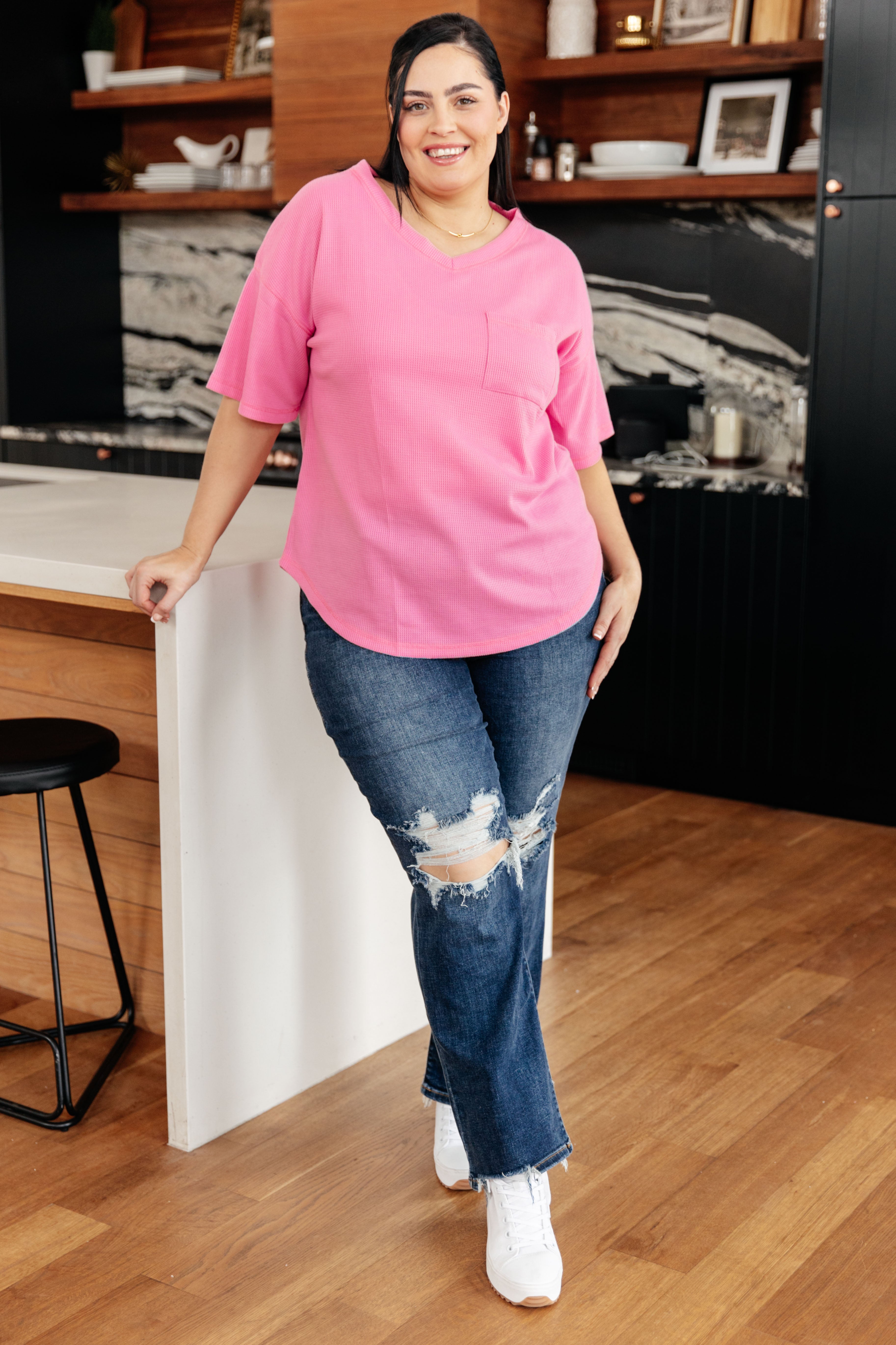 Plus size woman wearing bright pink Back Together V-Neck Top with pocket leaning on kitchen island, gallery image 0