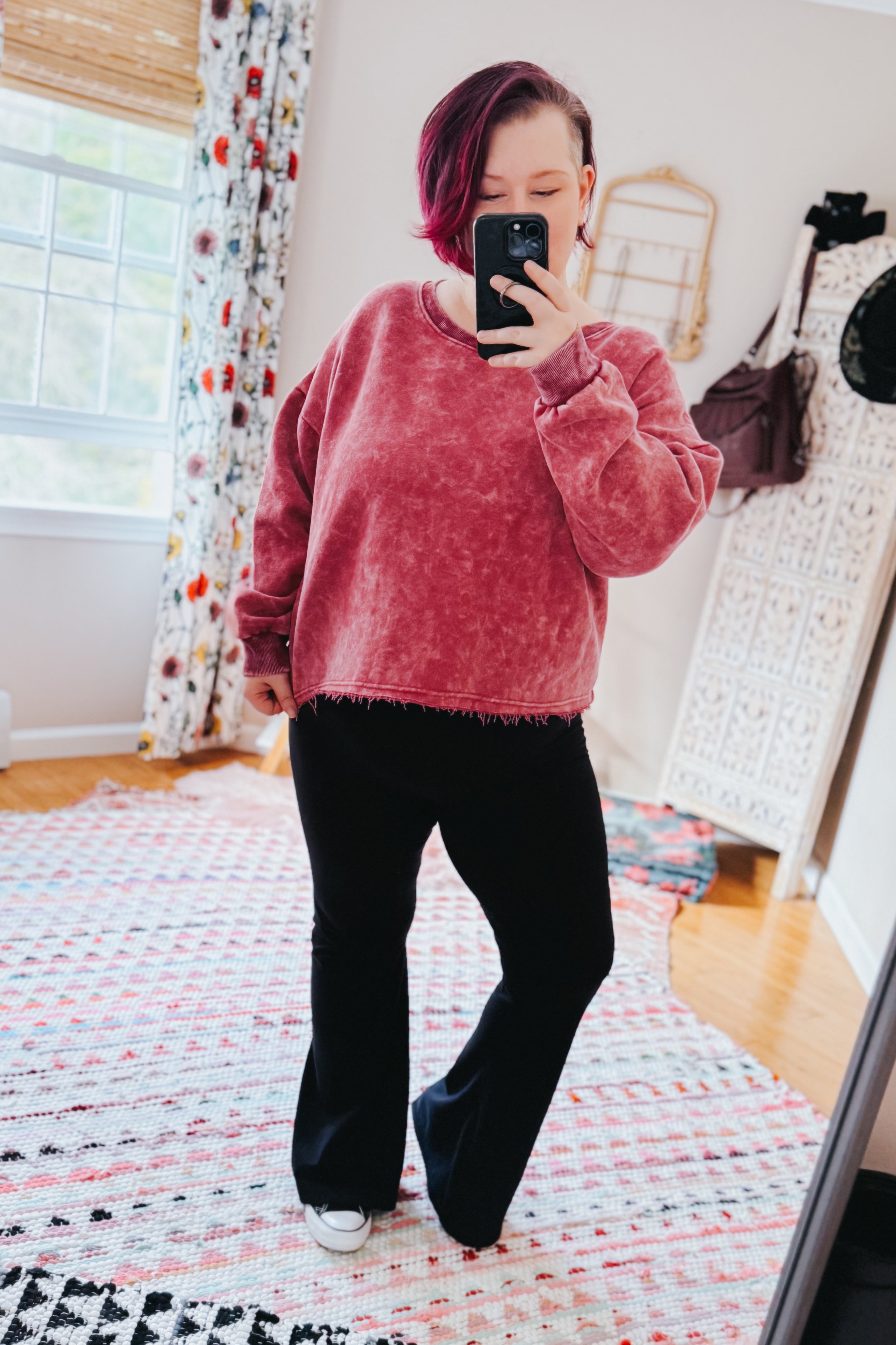Person with short magenta hair wearing Bad Company Acid Wash Cropped Pullover in berry, taking front-facing mirror selfie indoors