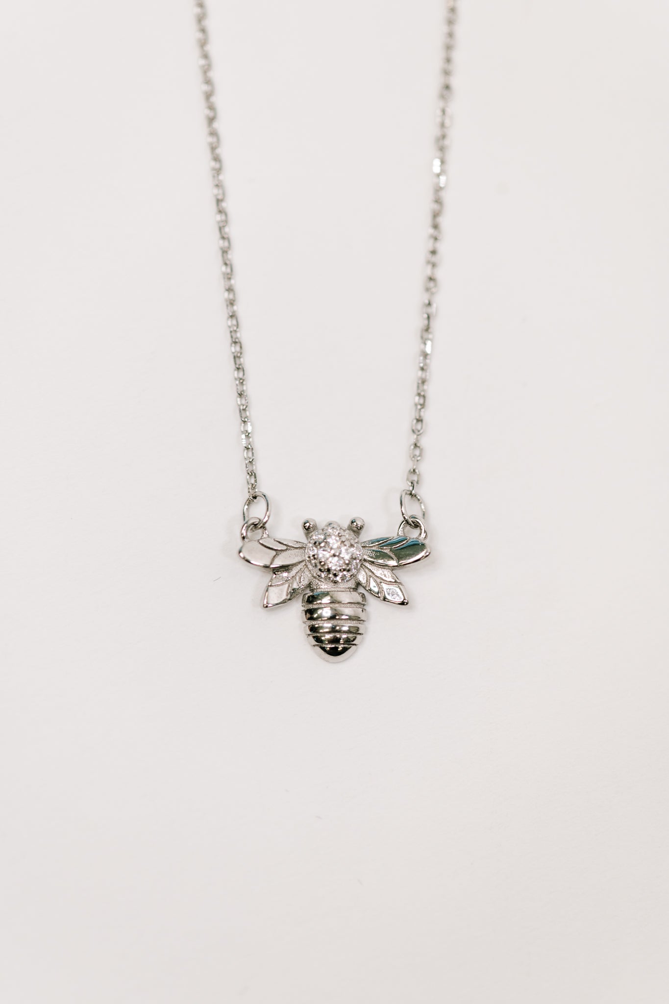 Delicate silver necklace featuring a bee pendant with sparkling stones on a fine chain in eclectic style