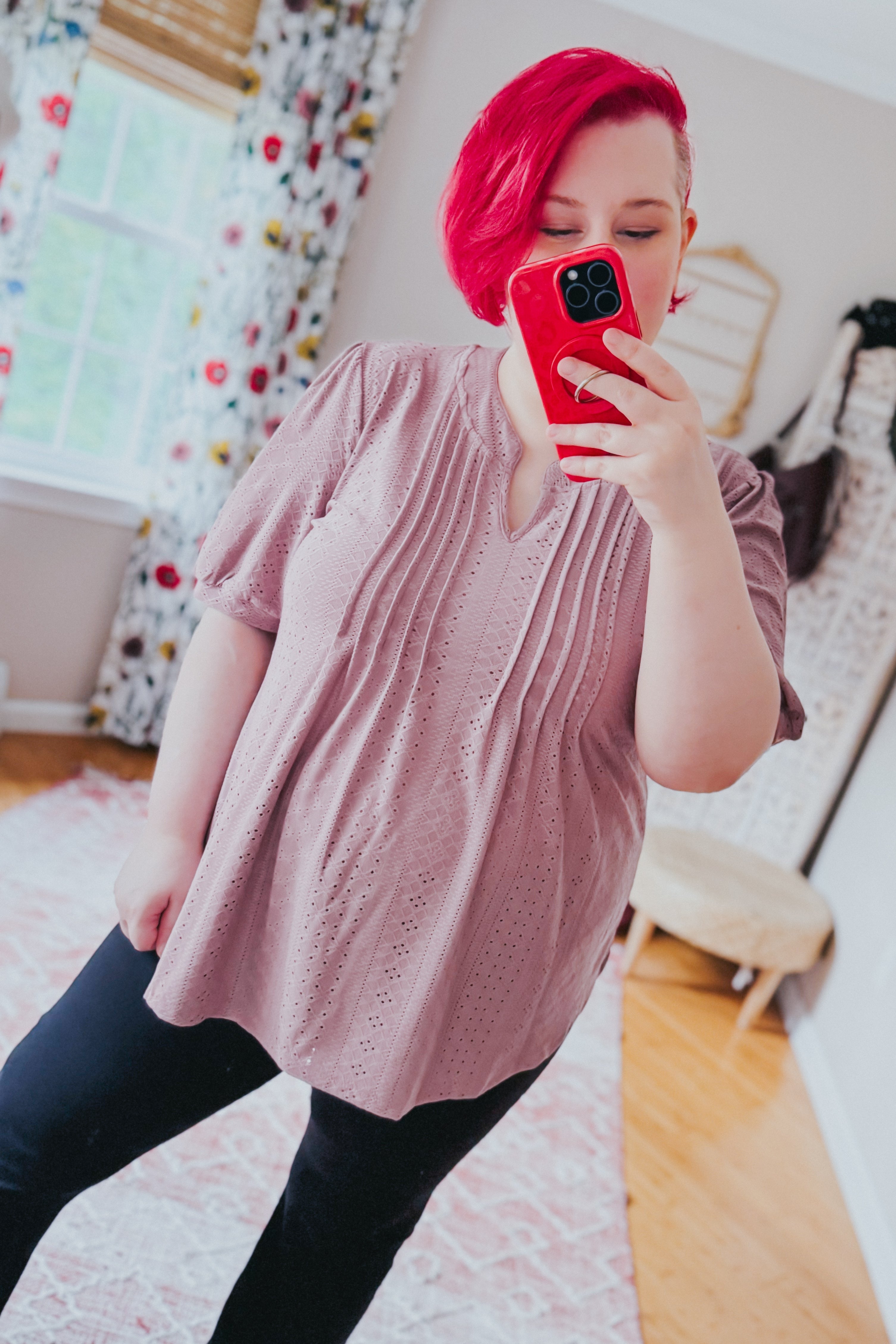 Light pink eyelet blouse with vertical pleats and short puff sleeves worn by woman taking mirror selfie in bright room