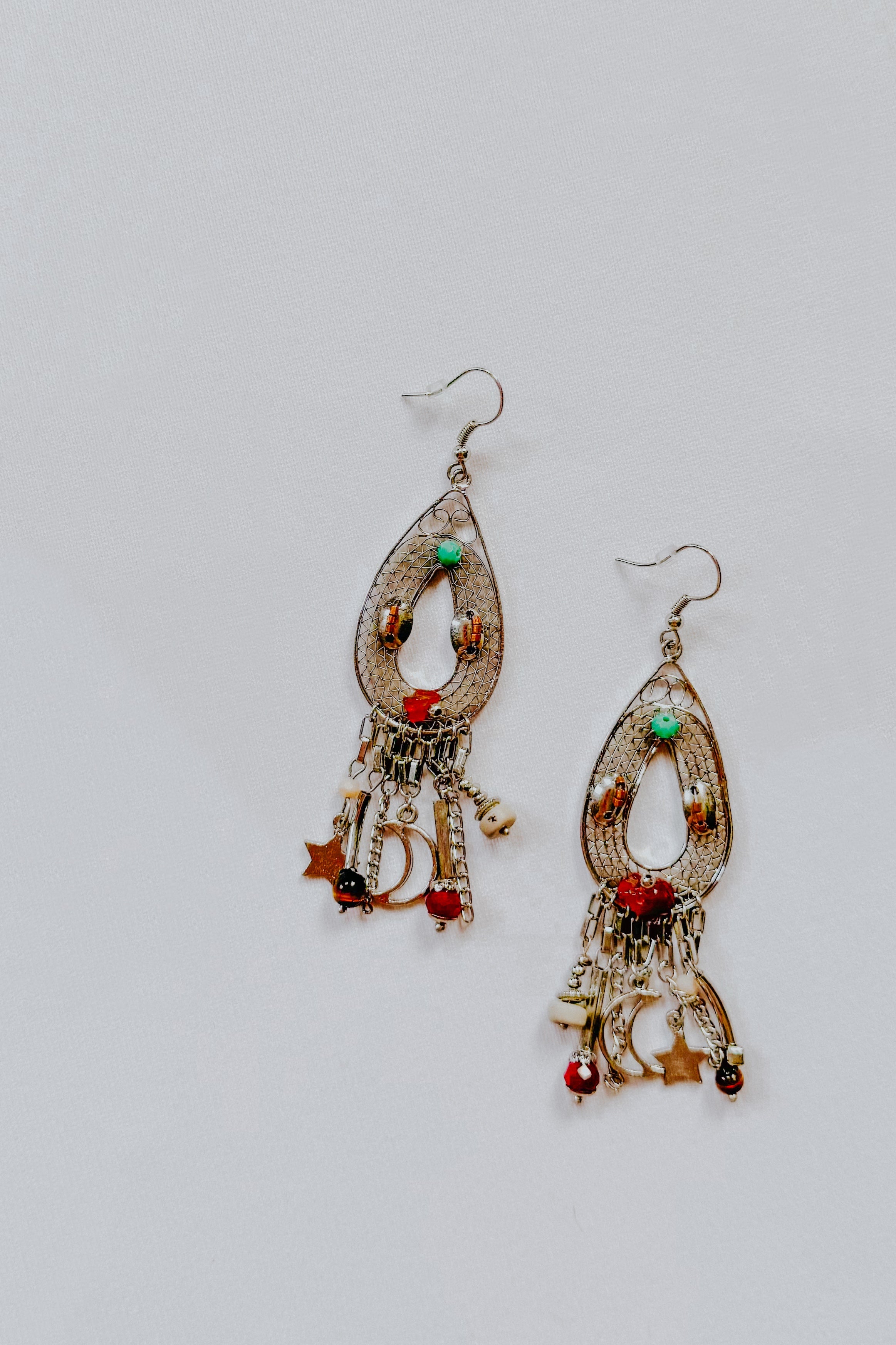 Pair of teardrop-shaped earrings with moon, star charms, and colorful beads on silver-tone metal hooks