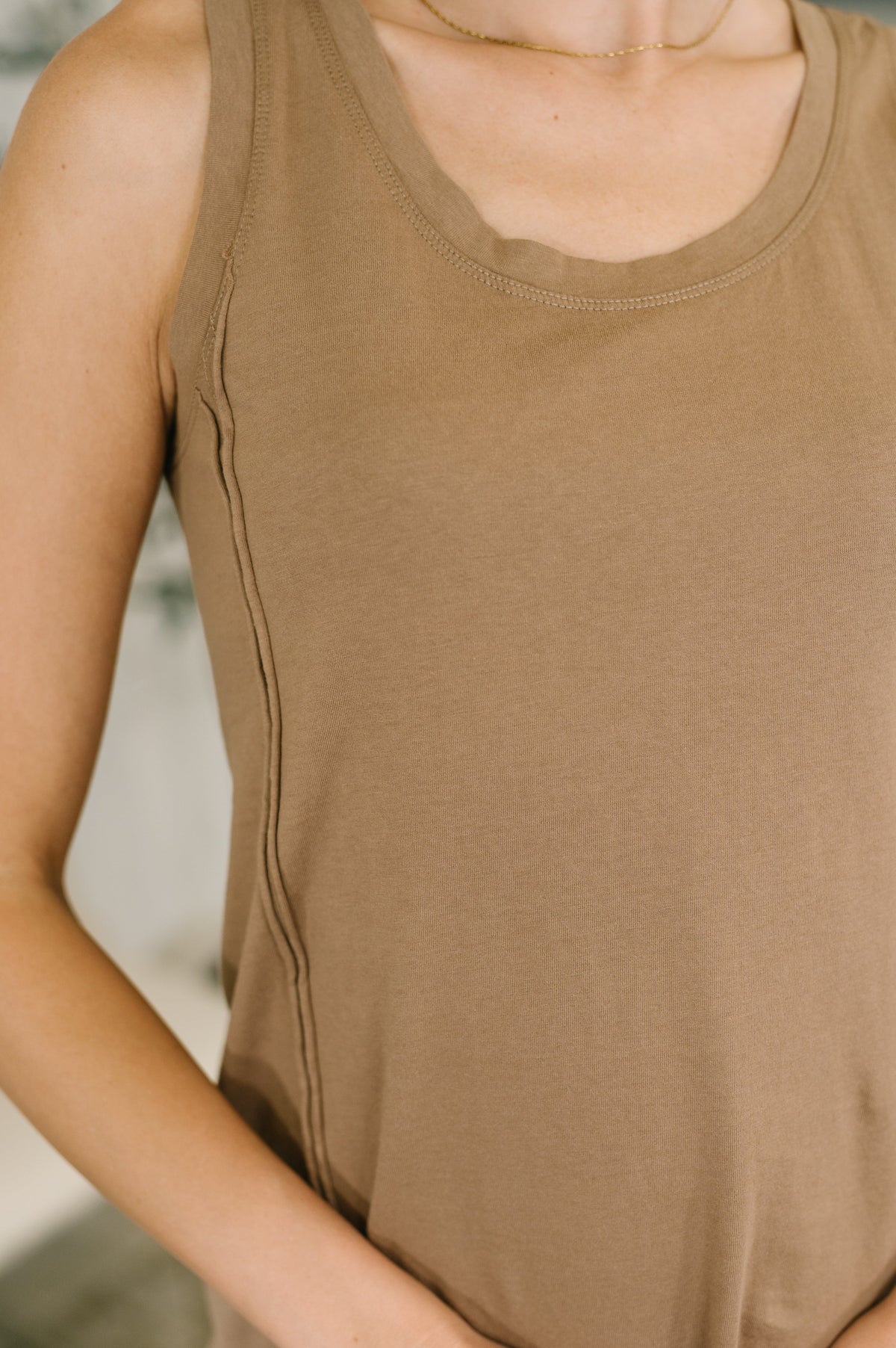 Close view of a woman wearing a mocha sleeveless scoop neck tank dress with a relaxed fit and soft jersey knit texture