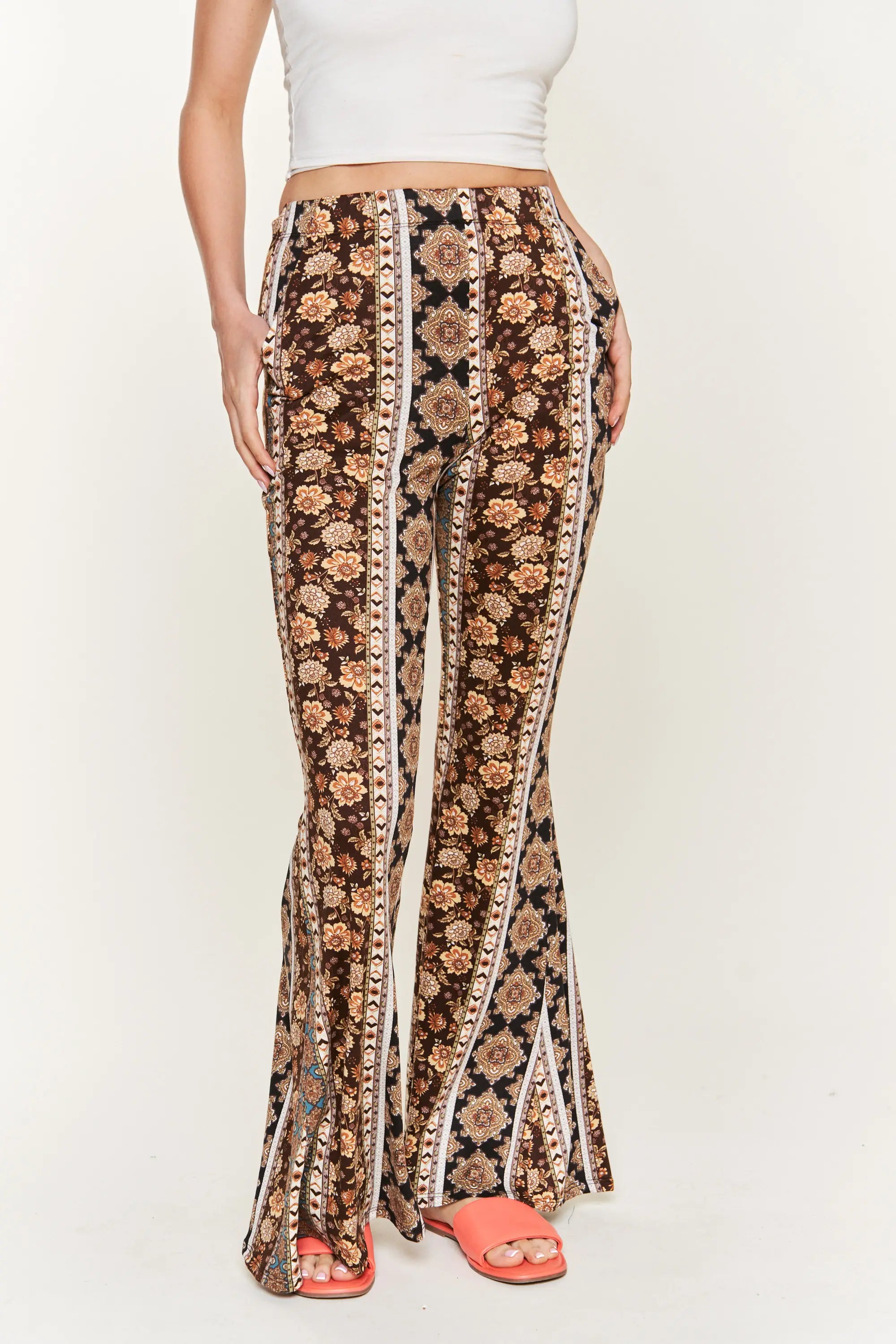 Front view of woman wearing high-waisted brown floral patterned flared pants with her hands in pockets