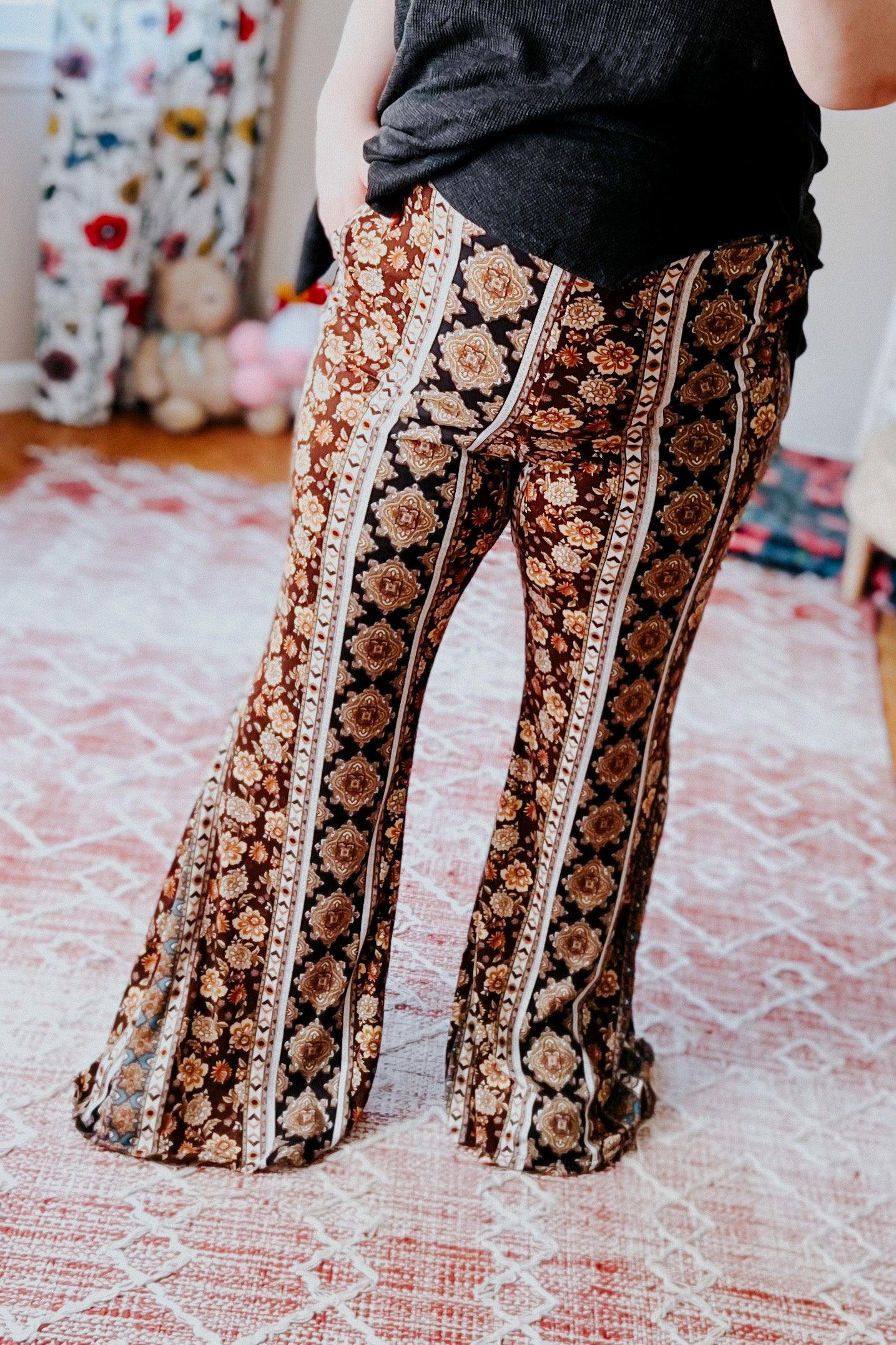 Close-up of woman wearing brown patterned flared pants with pockets standing on textured pink and white rug