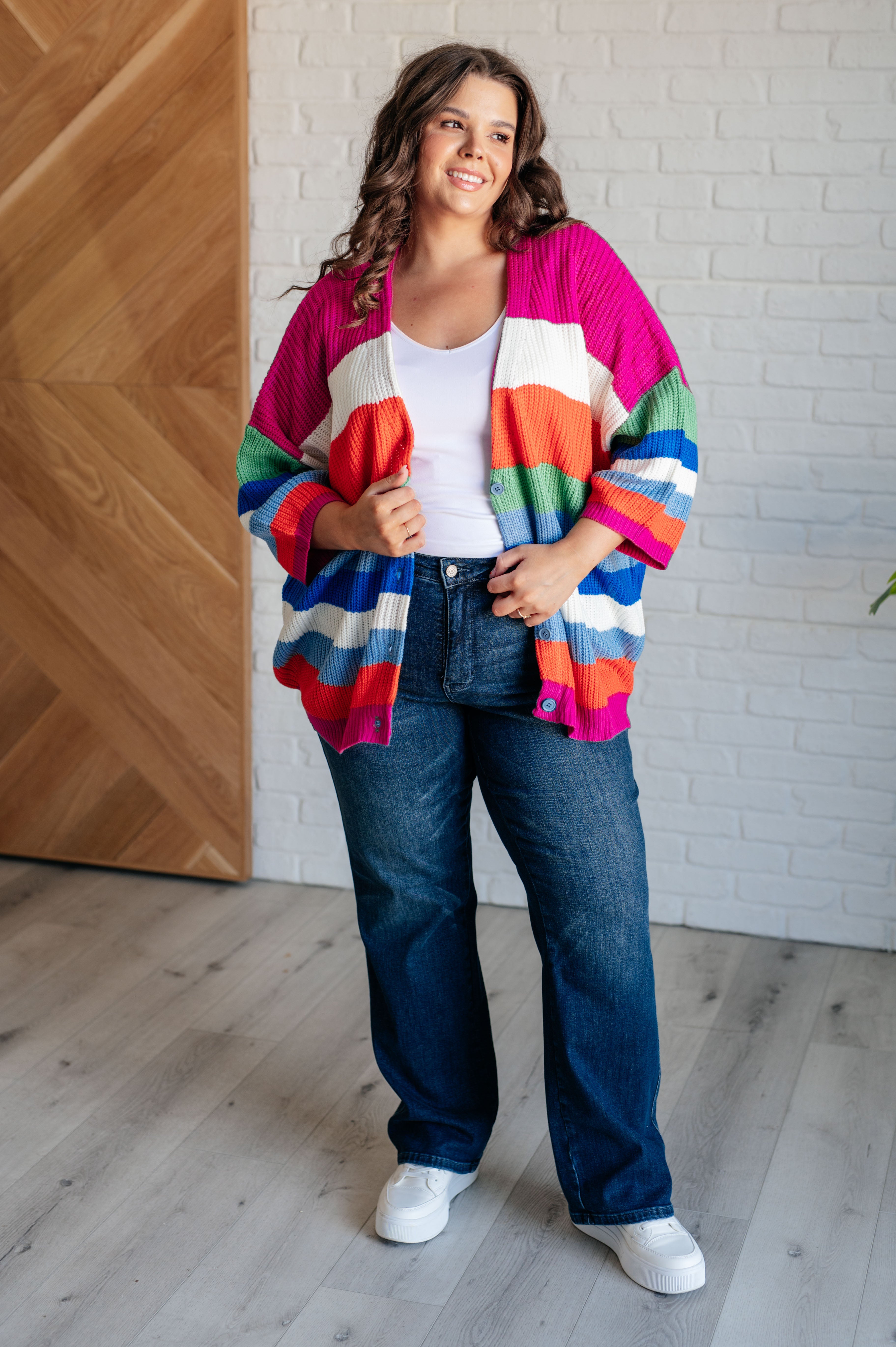Plus size woman wearing colorful oversized button-down cardigan with wide horizontal stripes in pink, orange, green, blue, and white