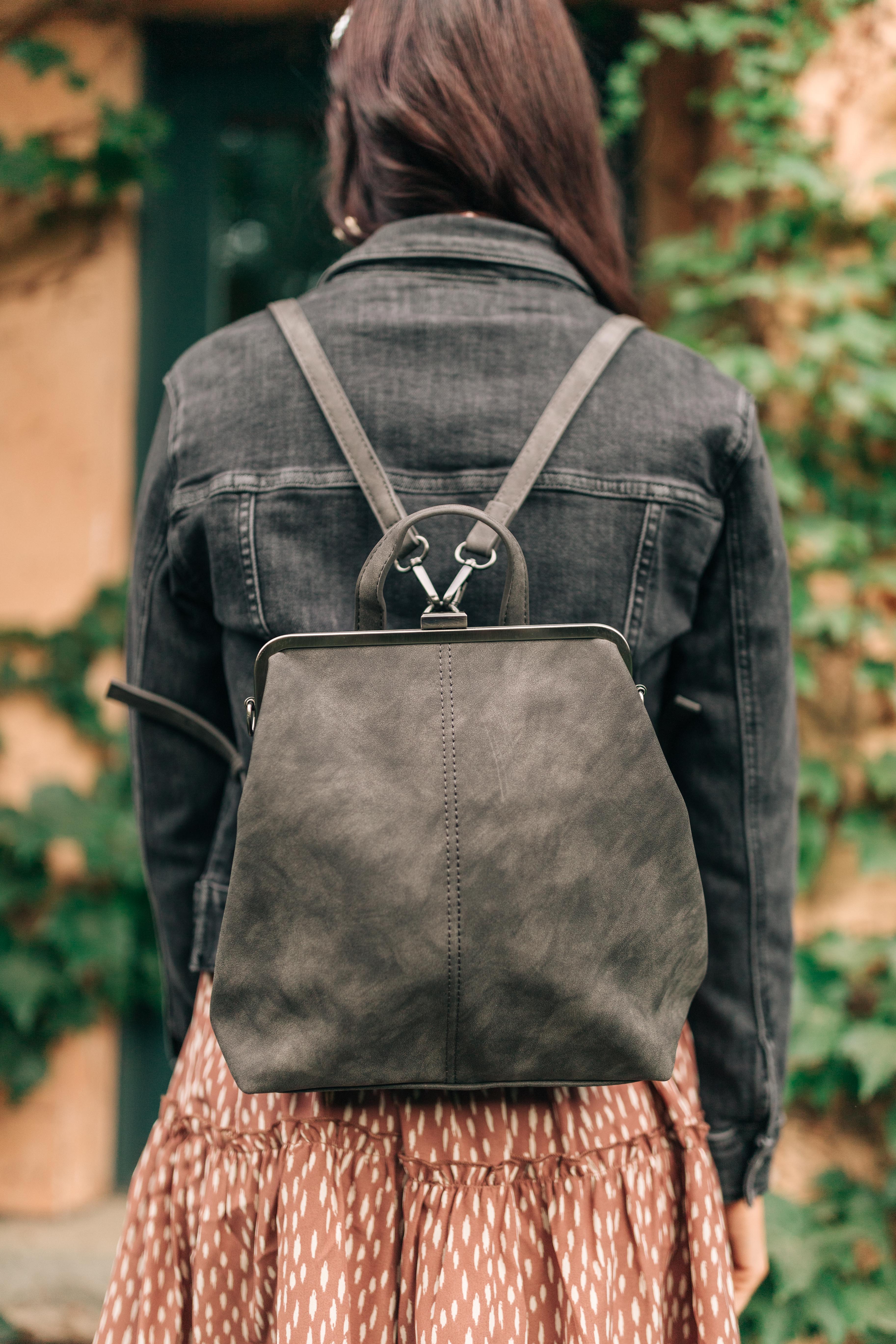 Rear view of person wearing charcoal small backpack with silver frame and soft texture outdoors