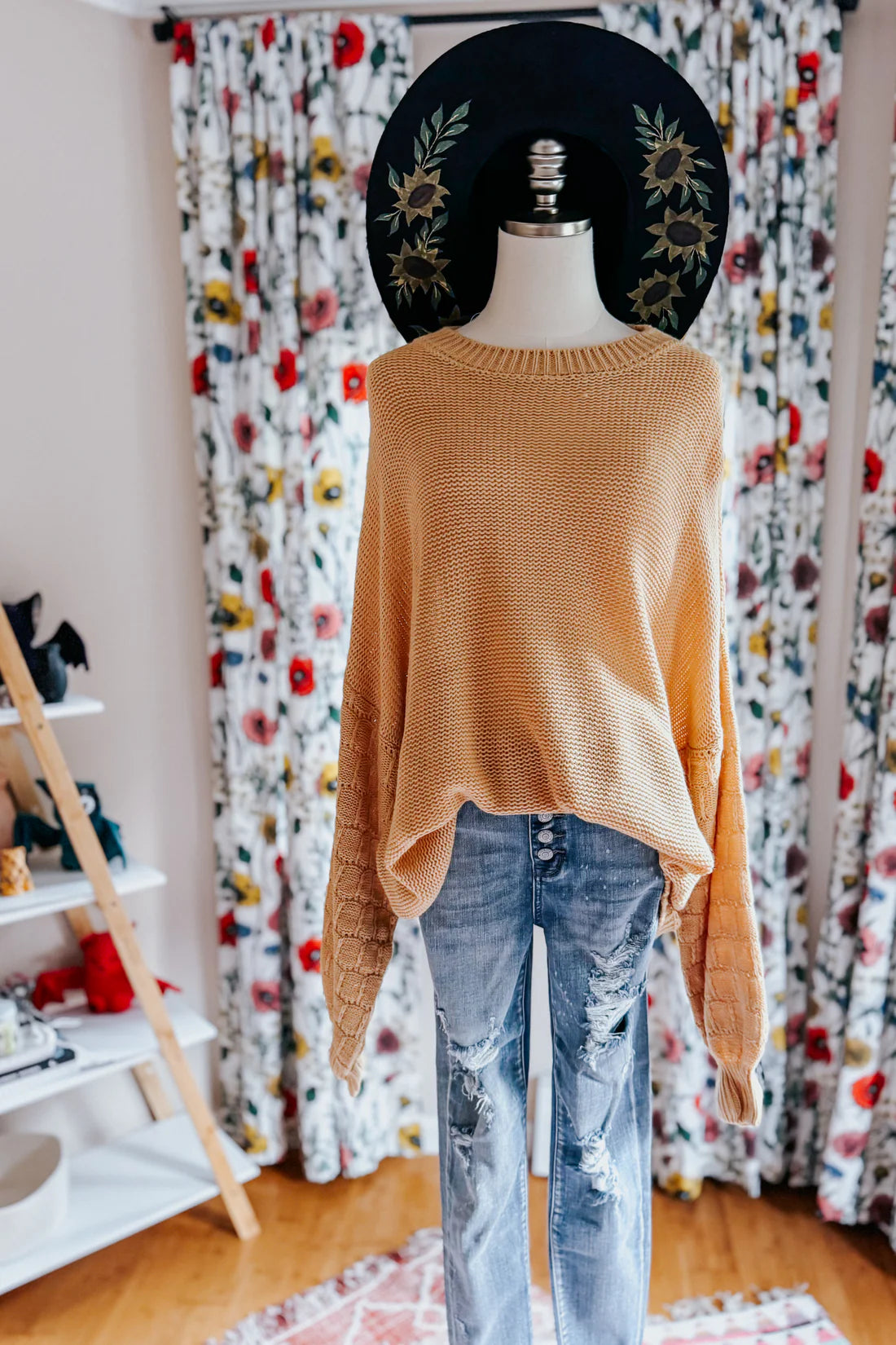 Wheat-colored bubble sleeve sweater paired with distressed light wash button fly jeans on mannequin indoors