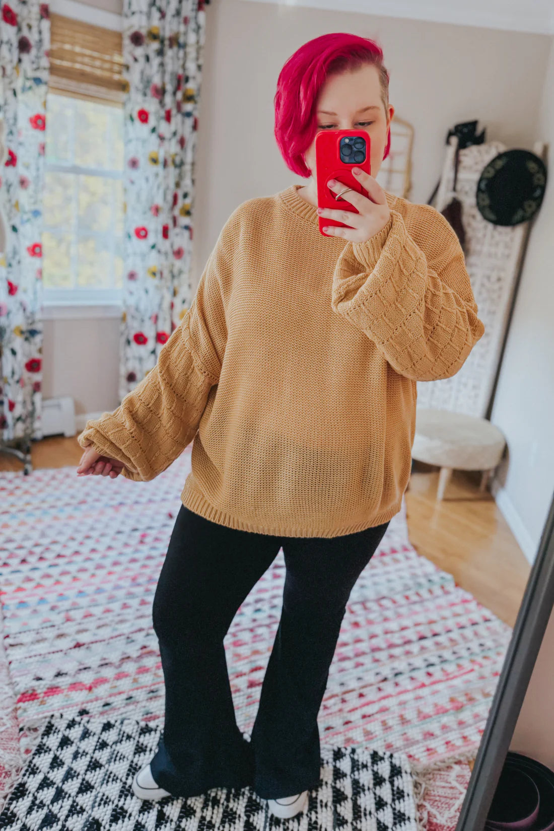 Woman wearing wheat-colored bubble sleeve sweater with textured knit paired with black pants and sneakers indoors