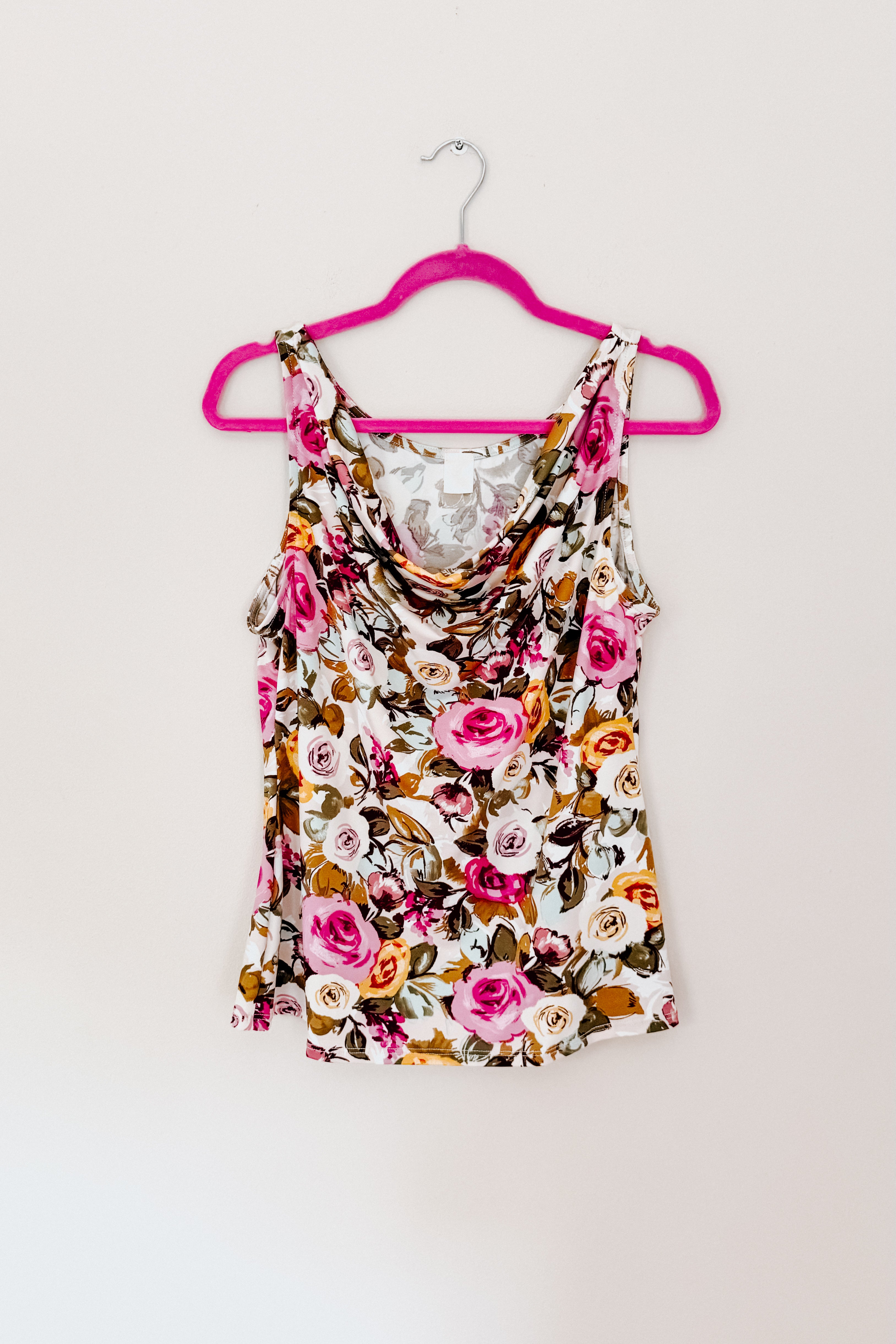 Floral cowl neck tank top with pink, cream, and brown roses hanging on bright pink hanger against beige wall